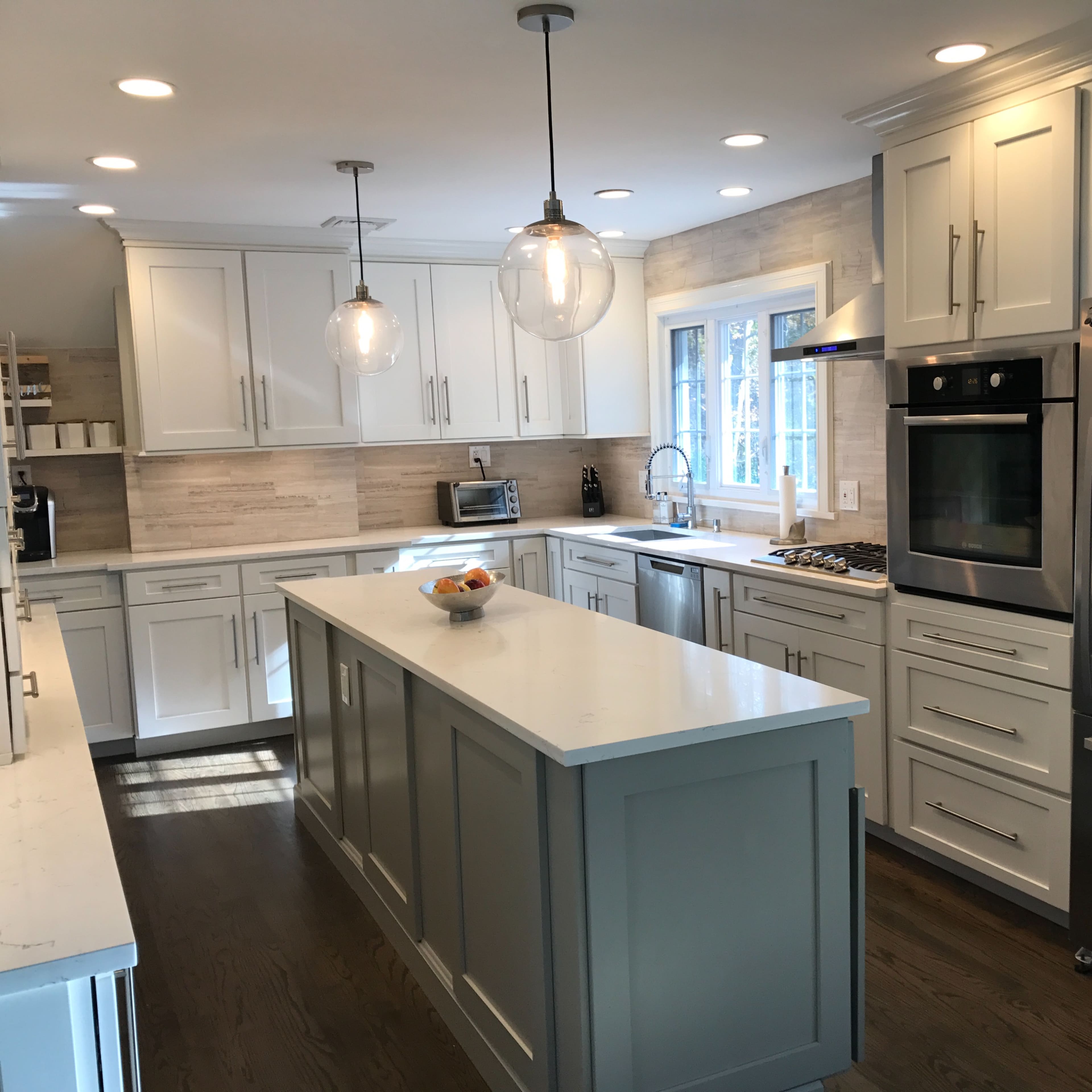 A modern kitchen with white cabinetry, stainless steel appliances, and a central island with a countertop.