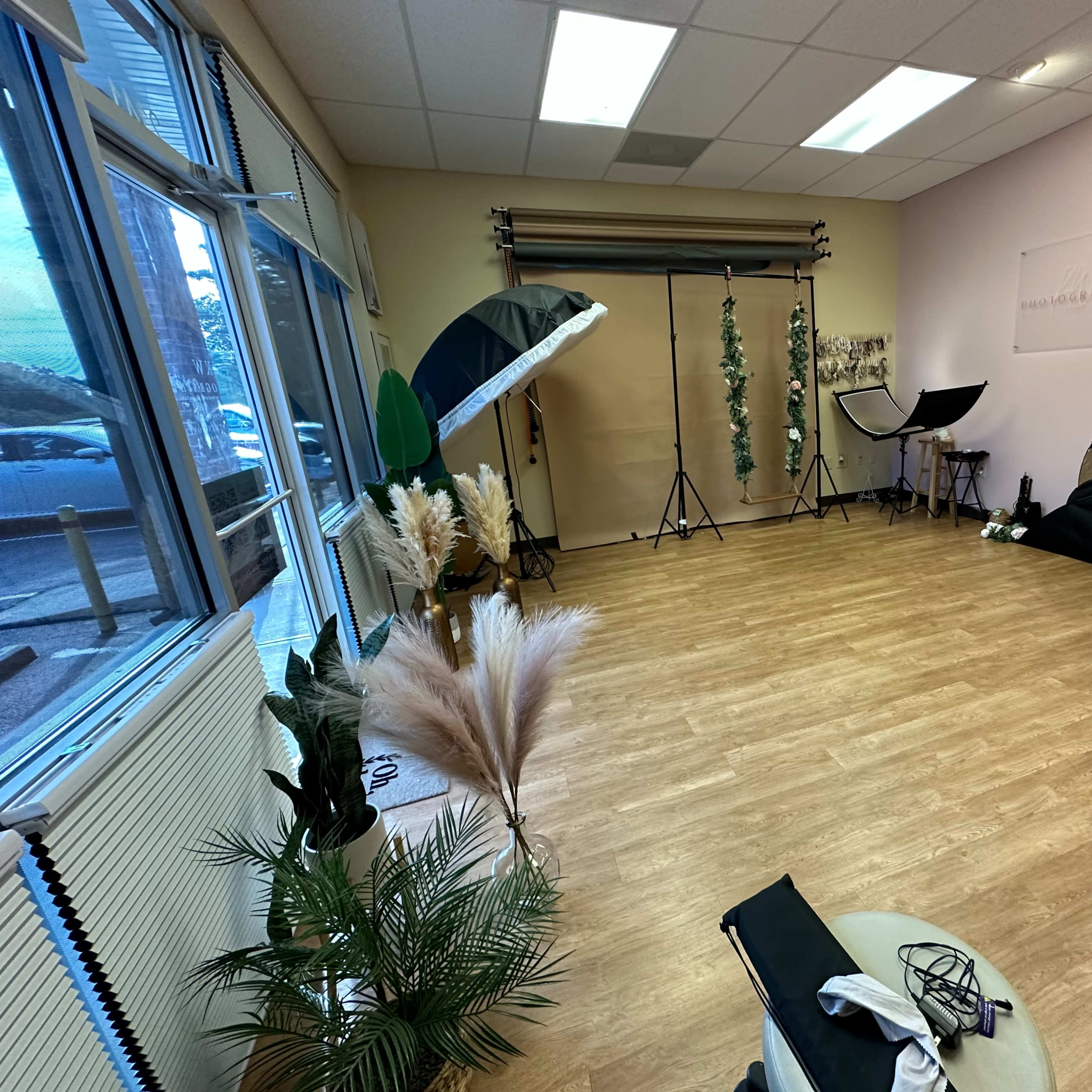 A photography studio with various lighting equipment, backdrops, and decorative elements arranged on a wooden floor.