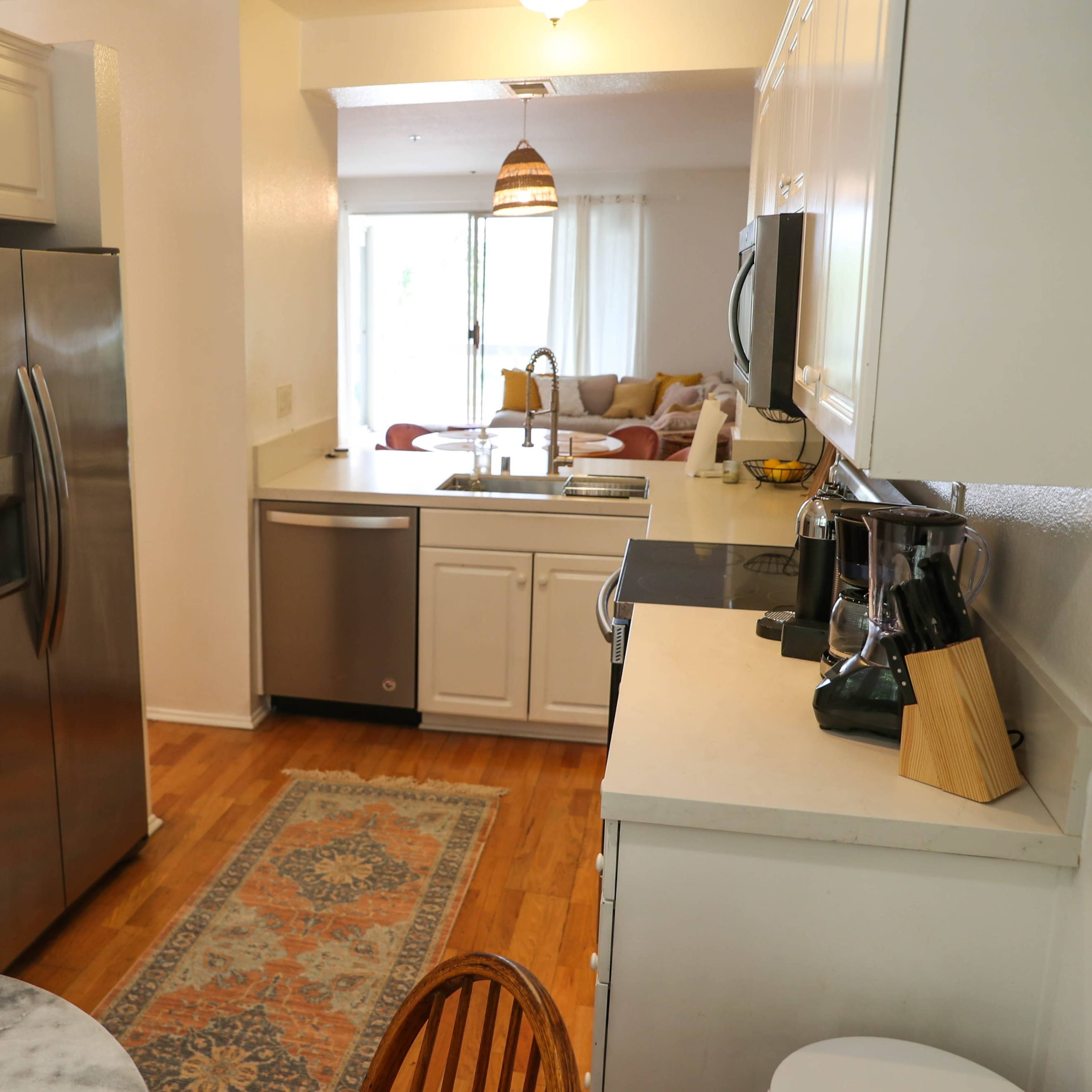 A modern kitchen with stainless steel appliances, white cabinetry, and a small dining table adorned with flowers.