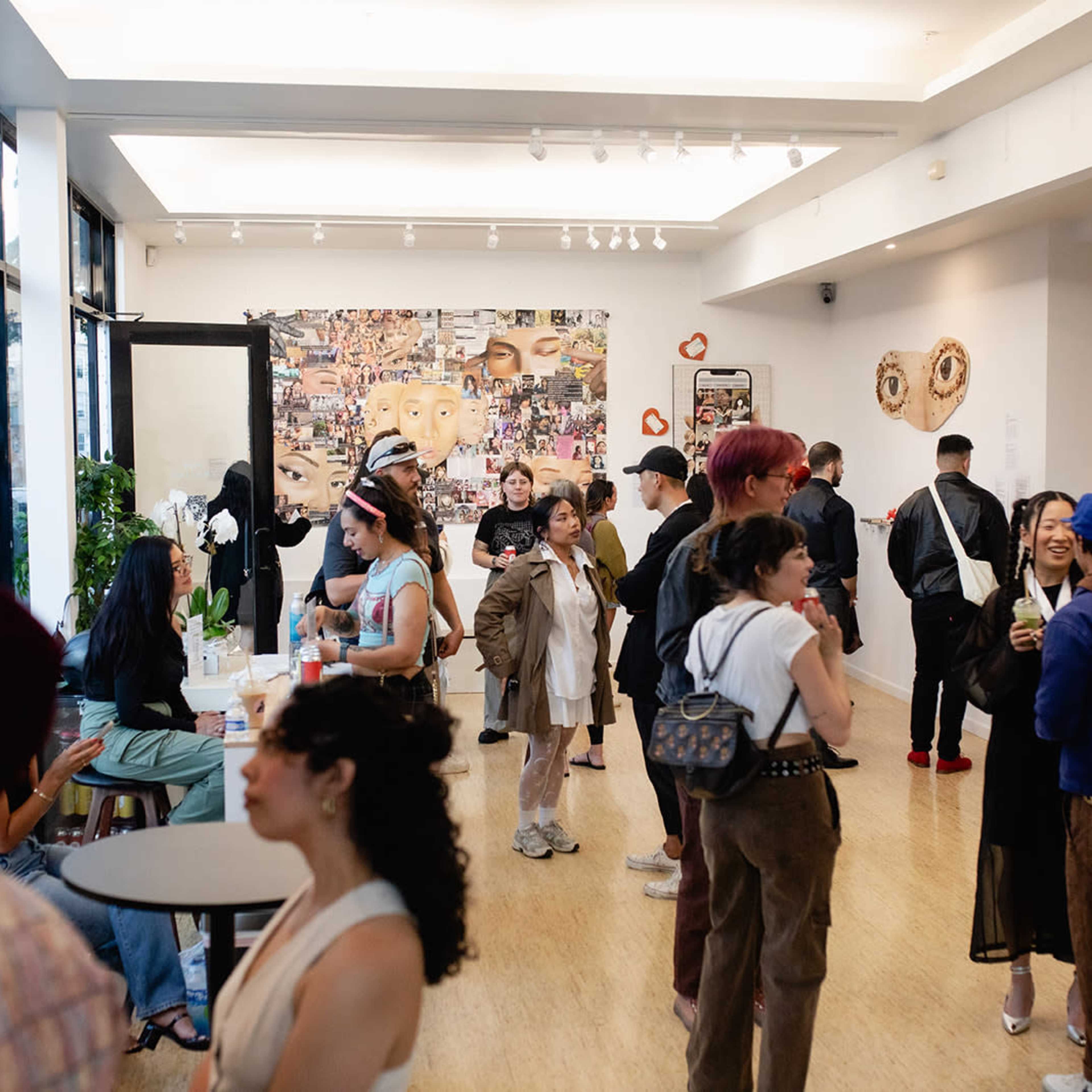 A lively art gallery with people socializing and engaging in conversation while surrounded by various artworks on the walls.