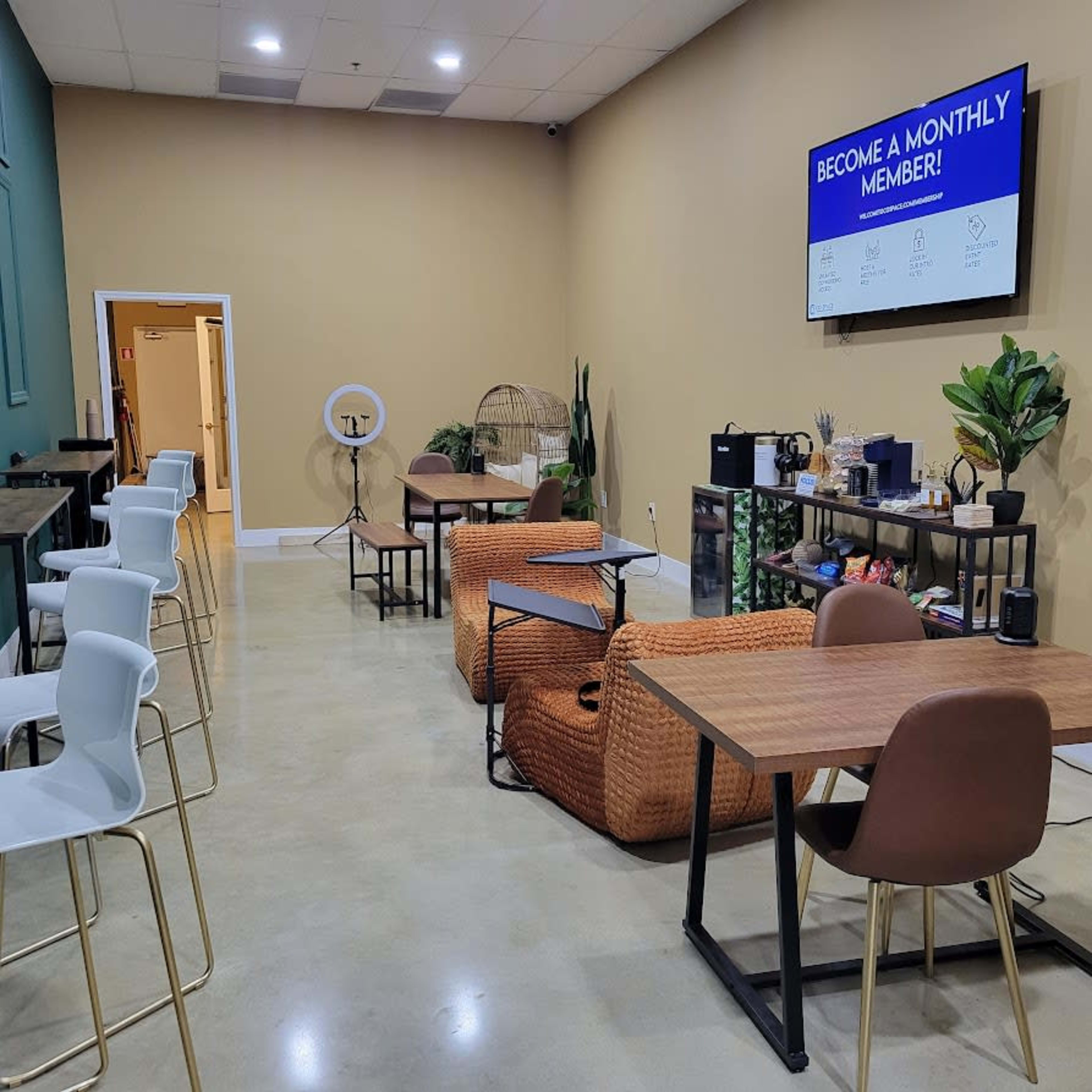 An interior space featuring seating areas, tables, and a large screen displaying a promotional message for membership.