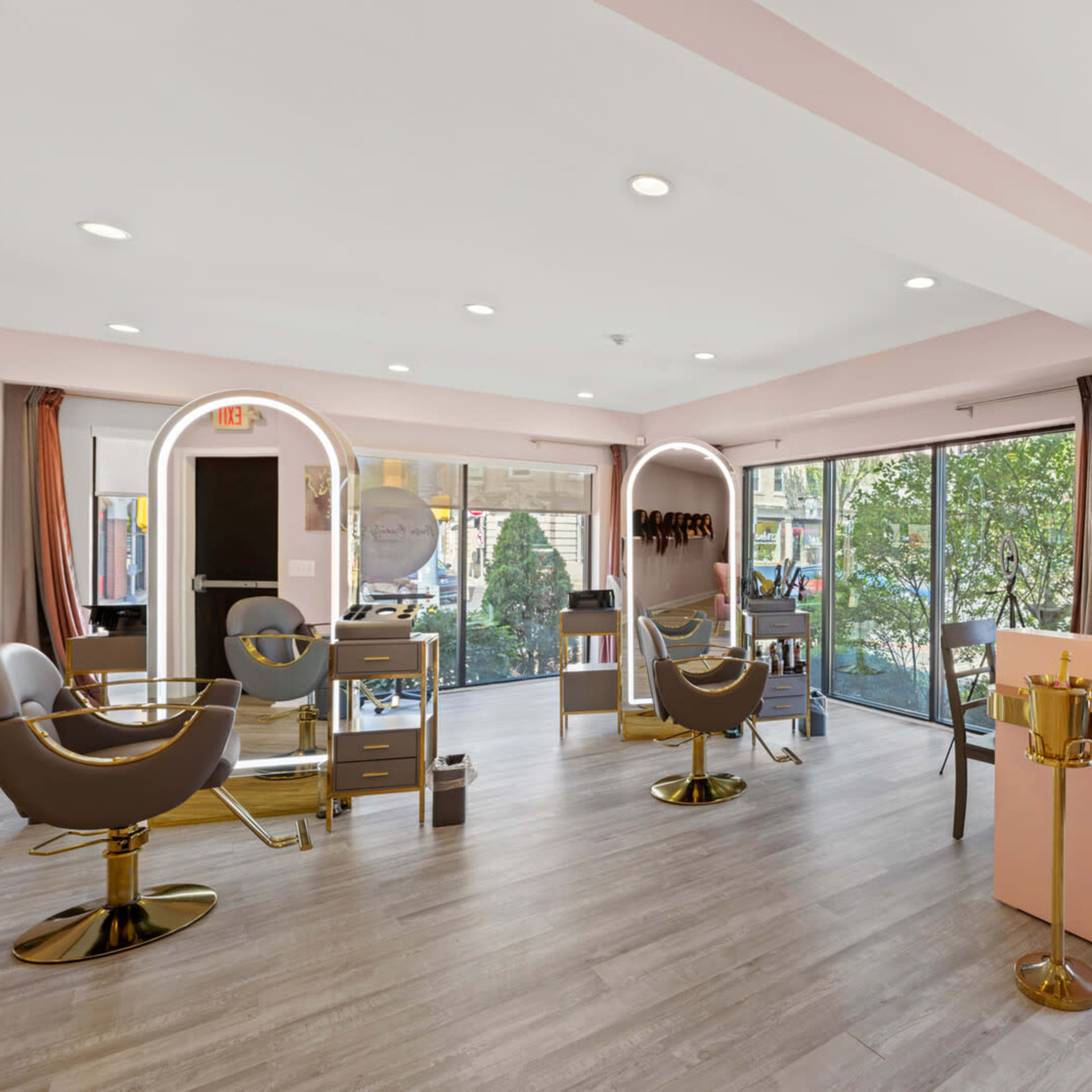 A modern salon interior with stylist chairs, a reception area, and large windows providing natural light.
