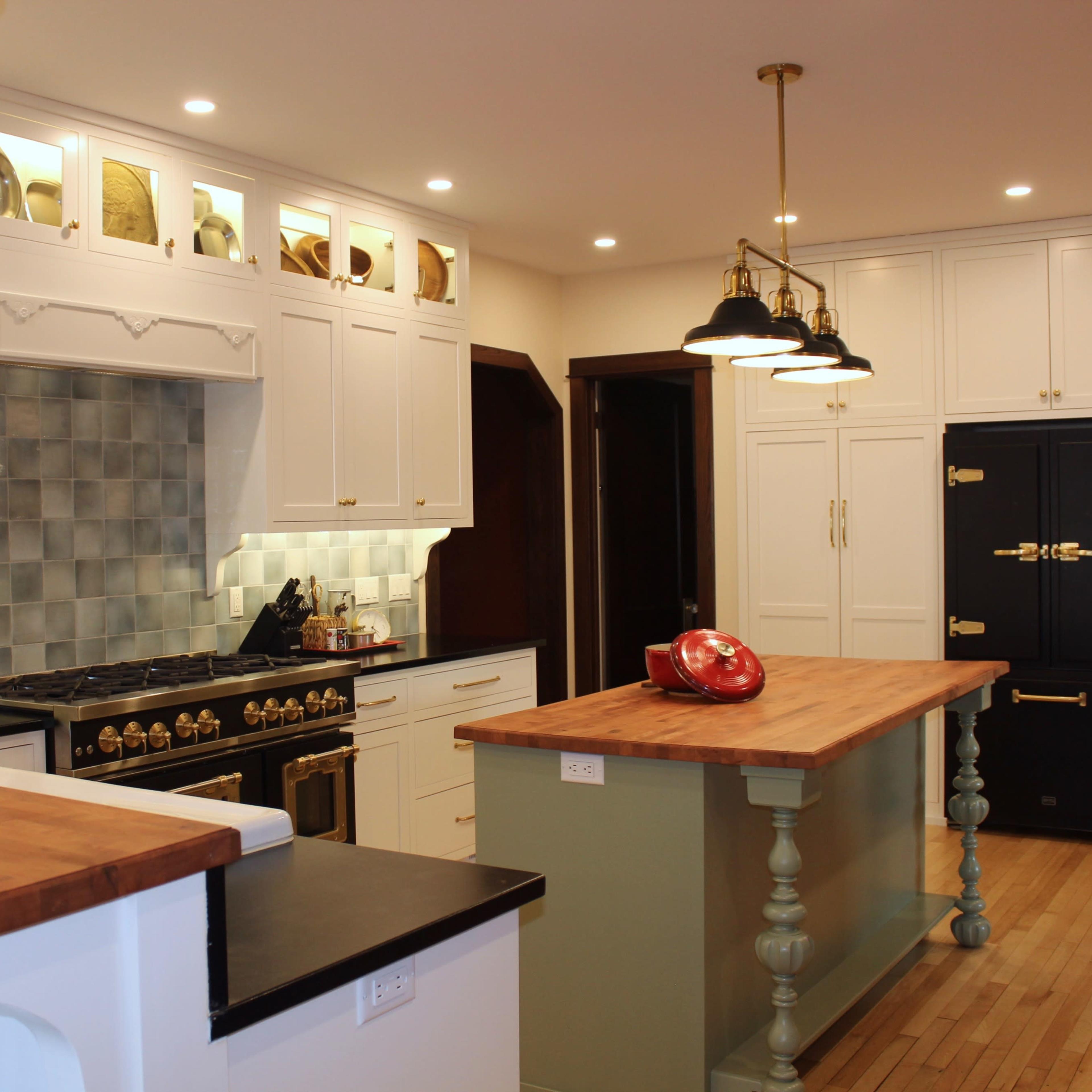 A modern kitchen with white cabinetry, a large wooden island, and stainless steel appliances.
