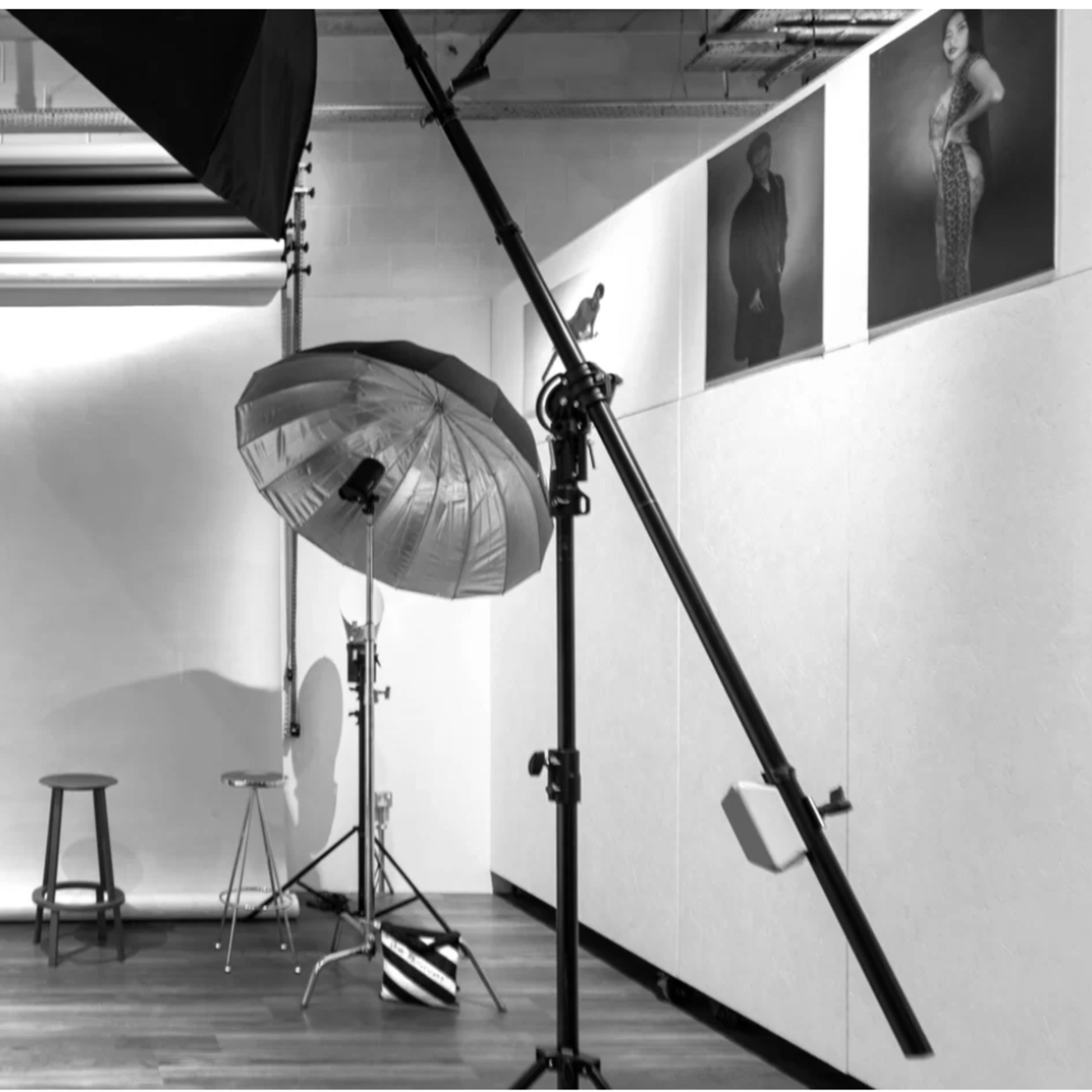A photography studio equipped with various lighting setups and backdrops, featuring stools and props arranged along the walls.