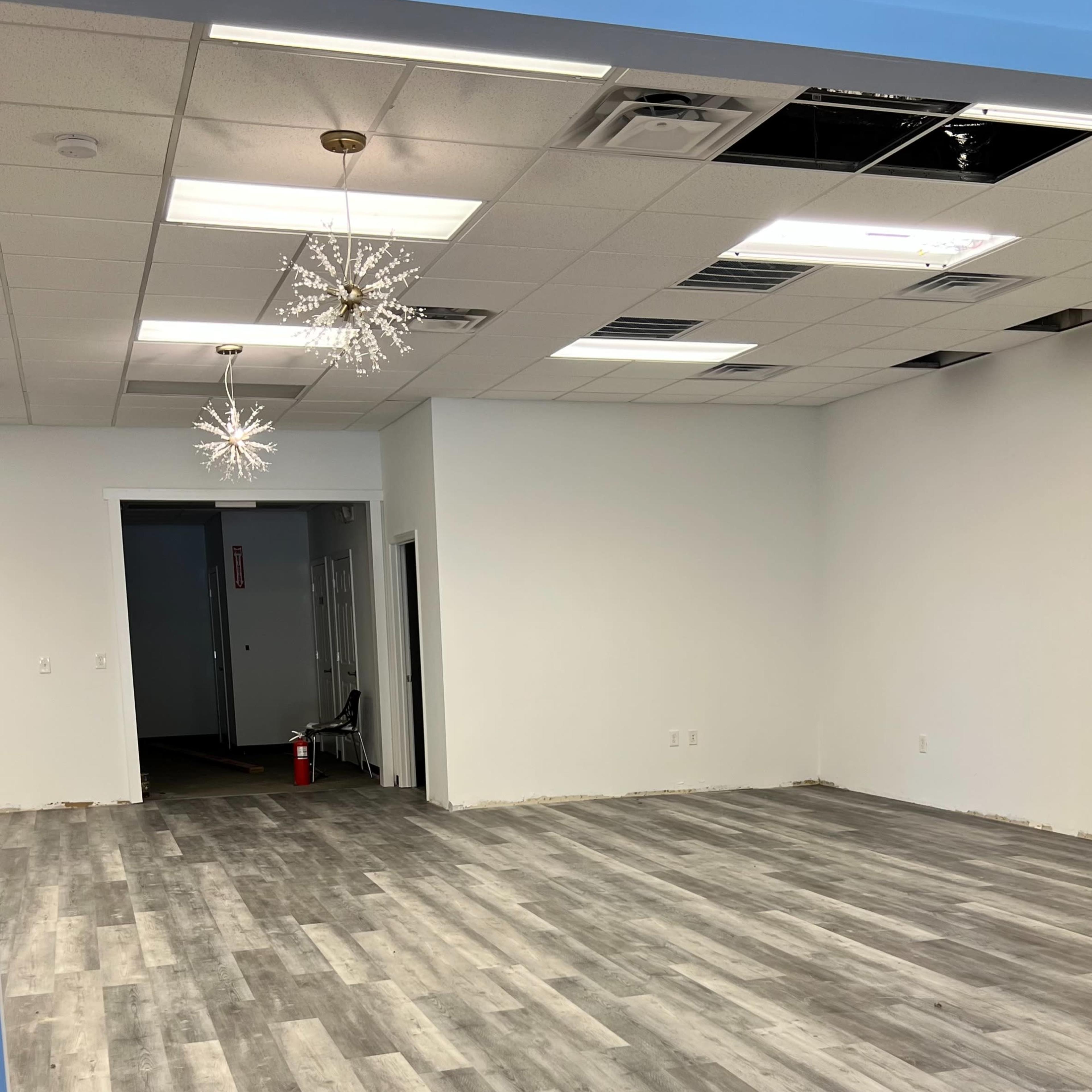 An empty room with gray laminate flooring and two decorative light fixtures hanging from the ceiling.