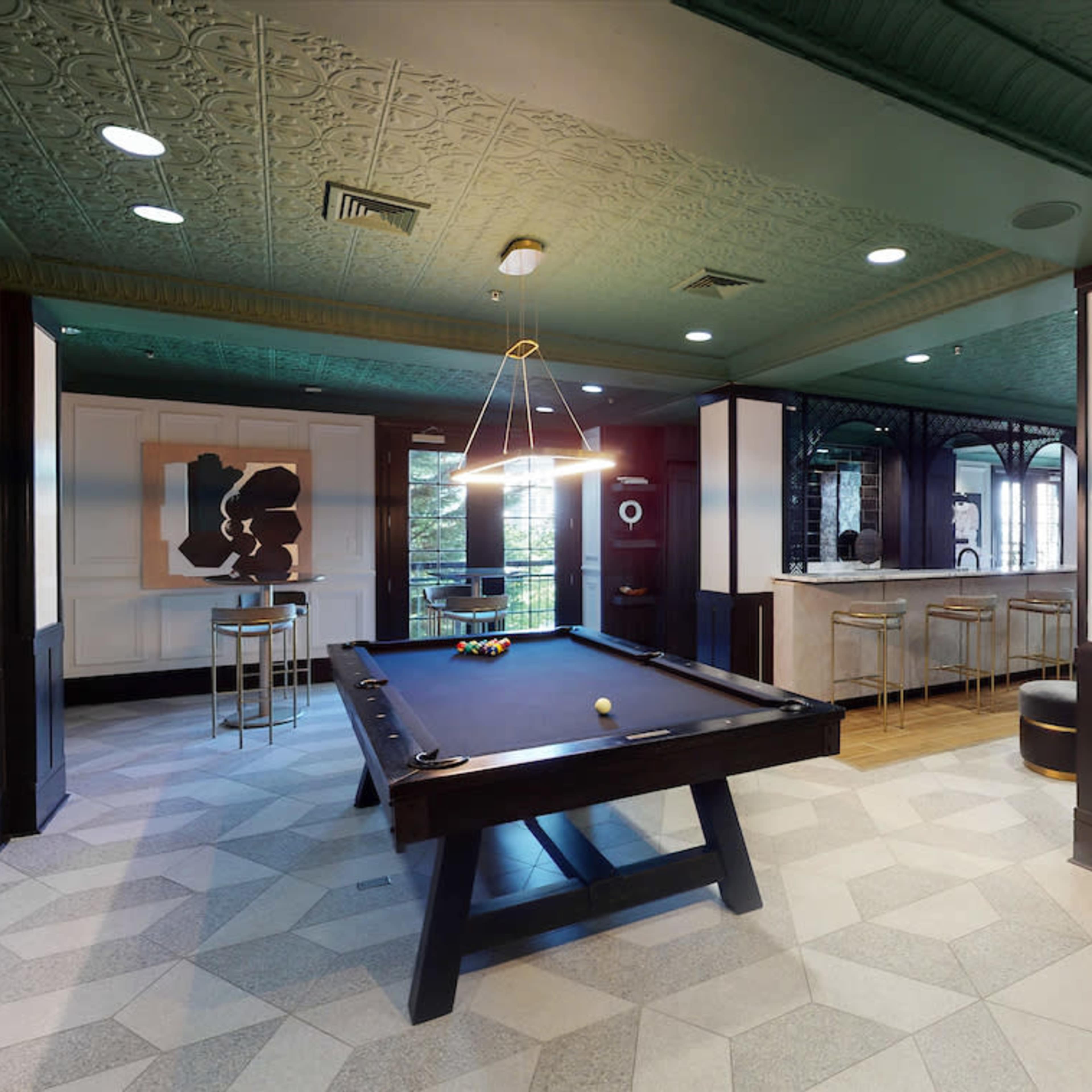 A recreational room featuring a pool table, a bar area with high stools, and a cozy seating arrangement.