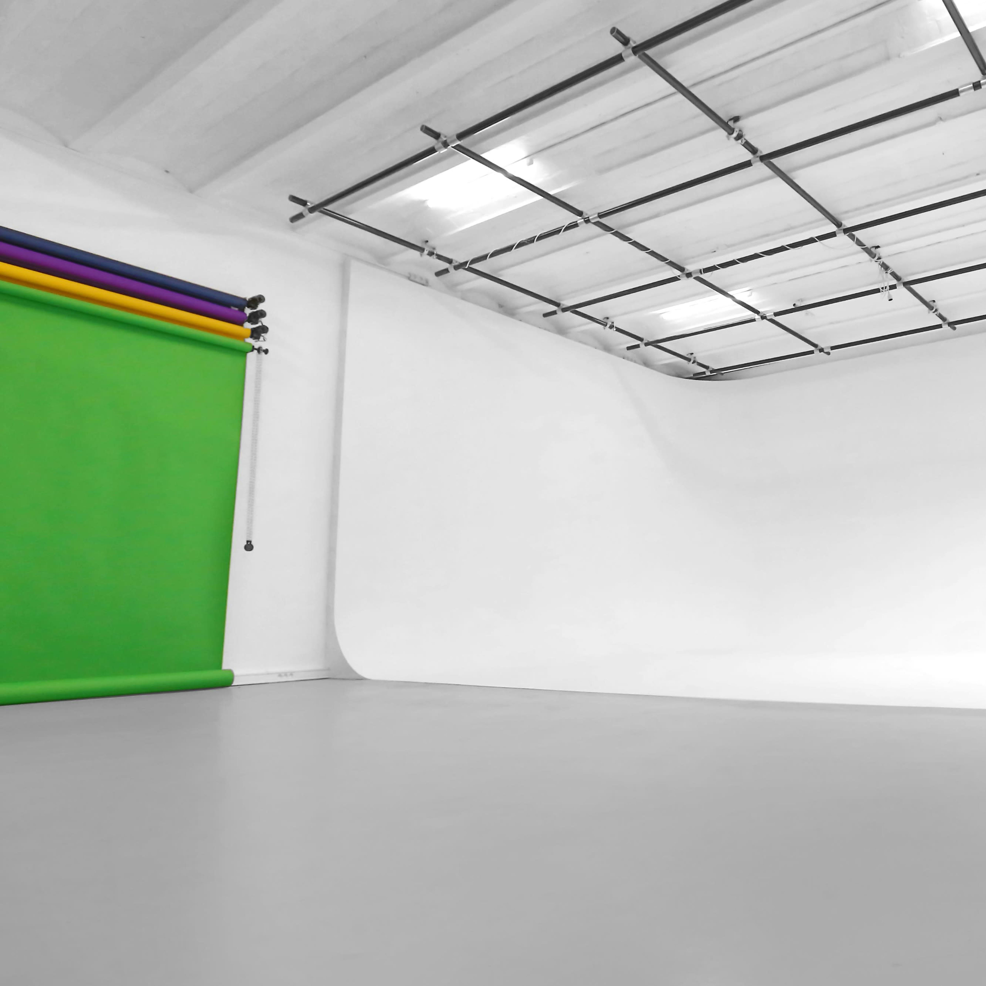 A bright and spacious photography studio with a seamless white backdrop and a green screen.