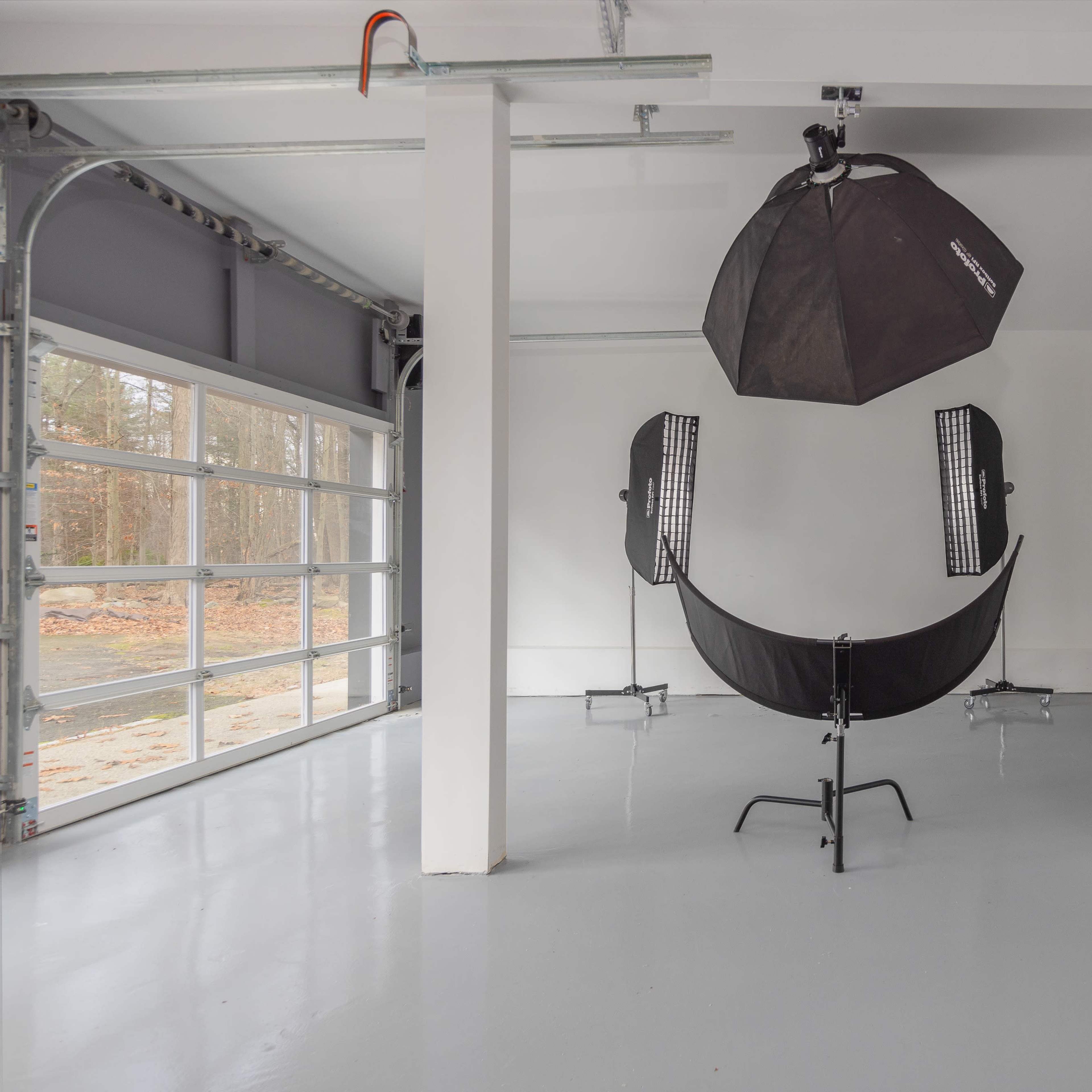 A spacious indoor studio with photography lighting equipment set up against a white wall.