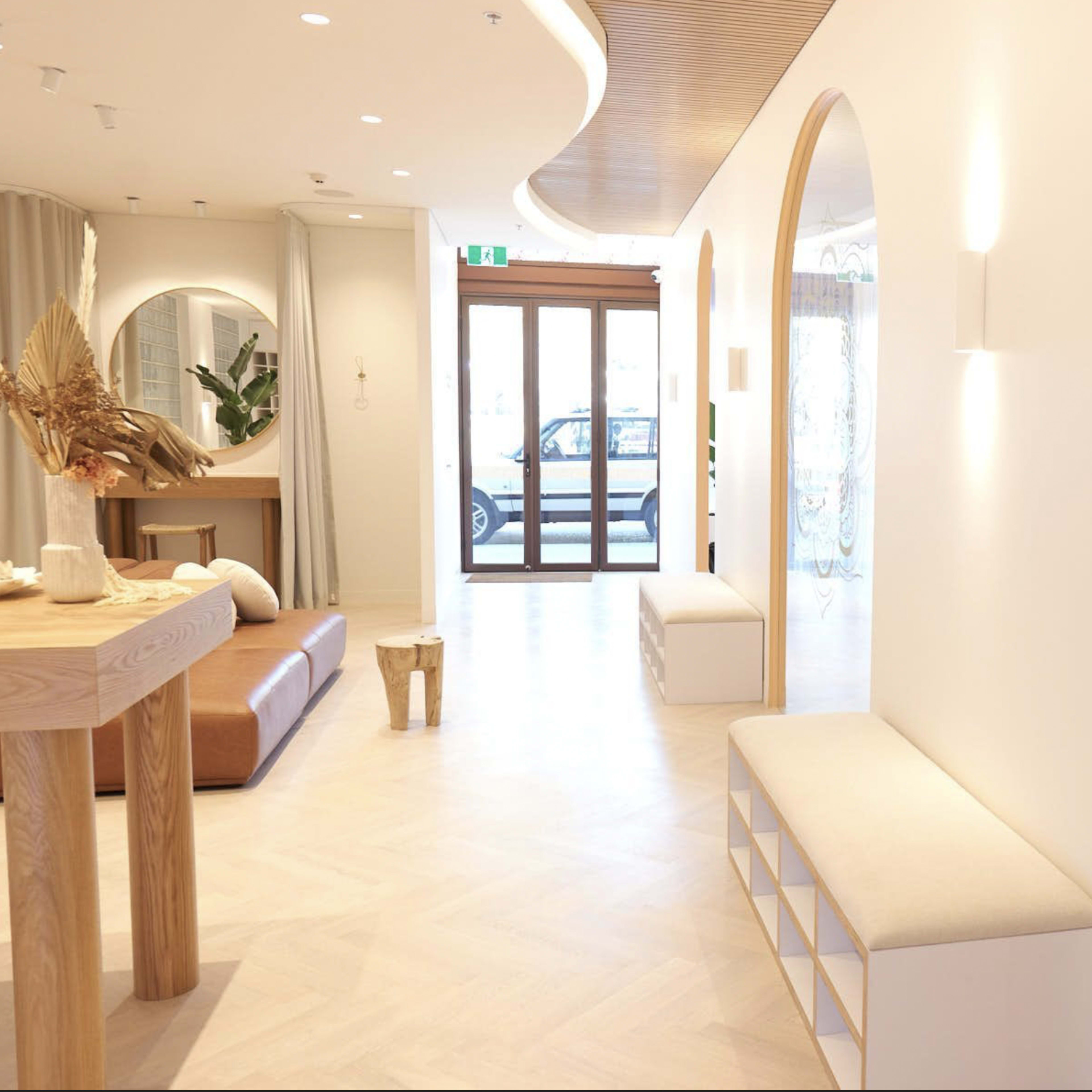 A modern, well-lit yoga studio with a minimalist interior, featuring a seating area, a large mirror, and yoga mats arranged on the floor.