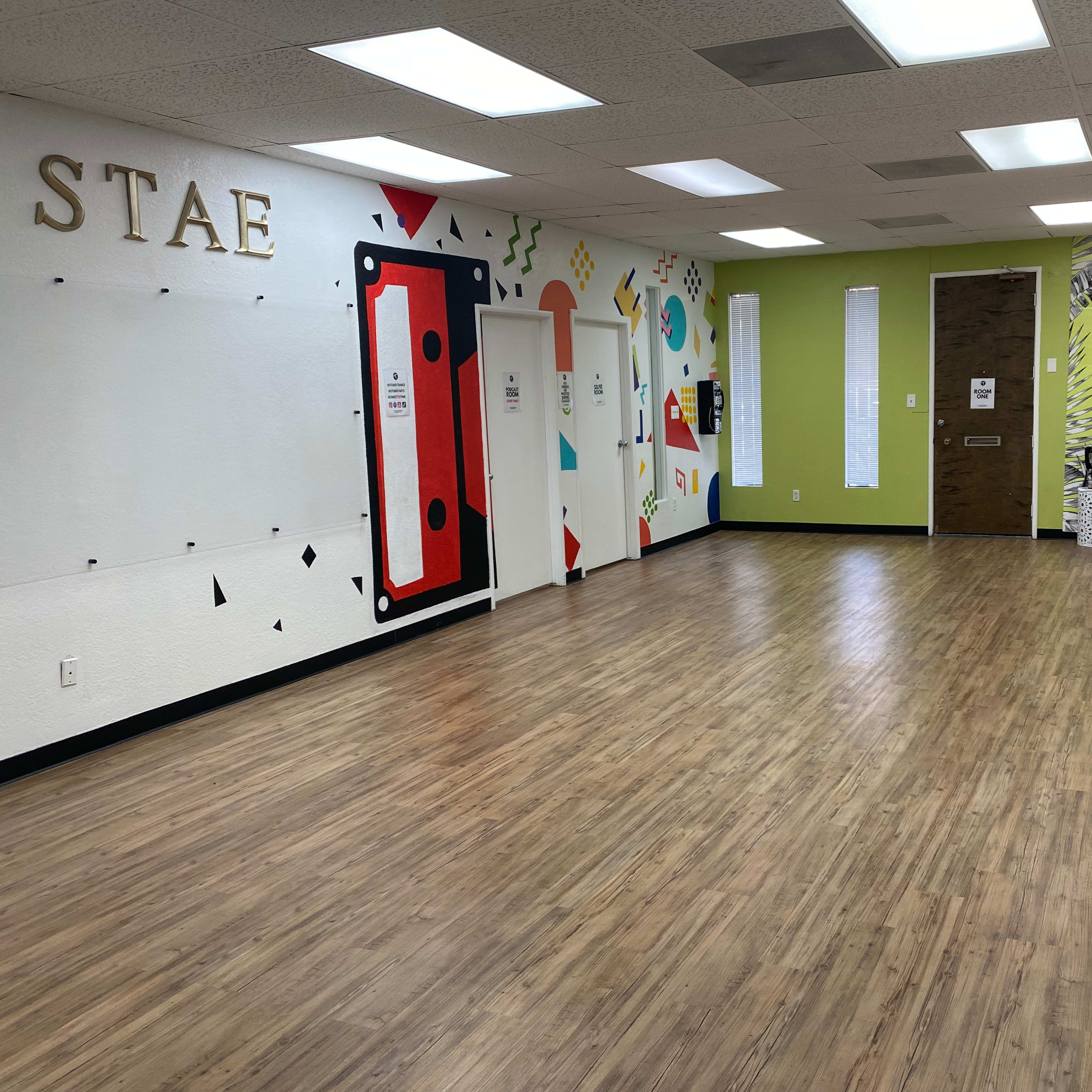 A spacious, brightly lit room with colorful wall art and a seating area in one corner.