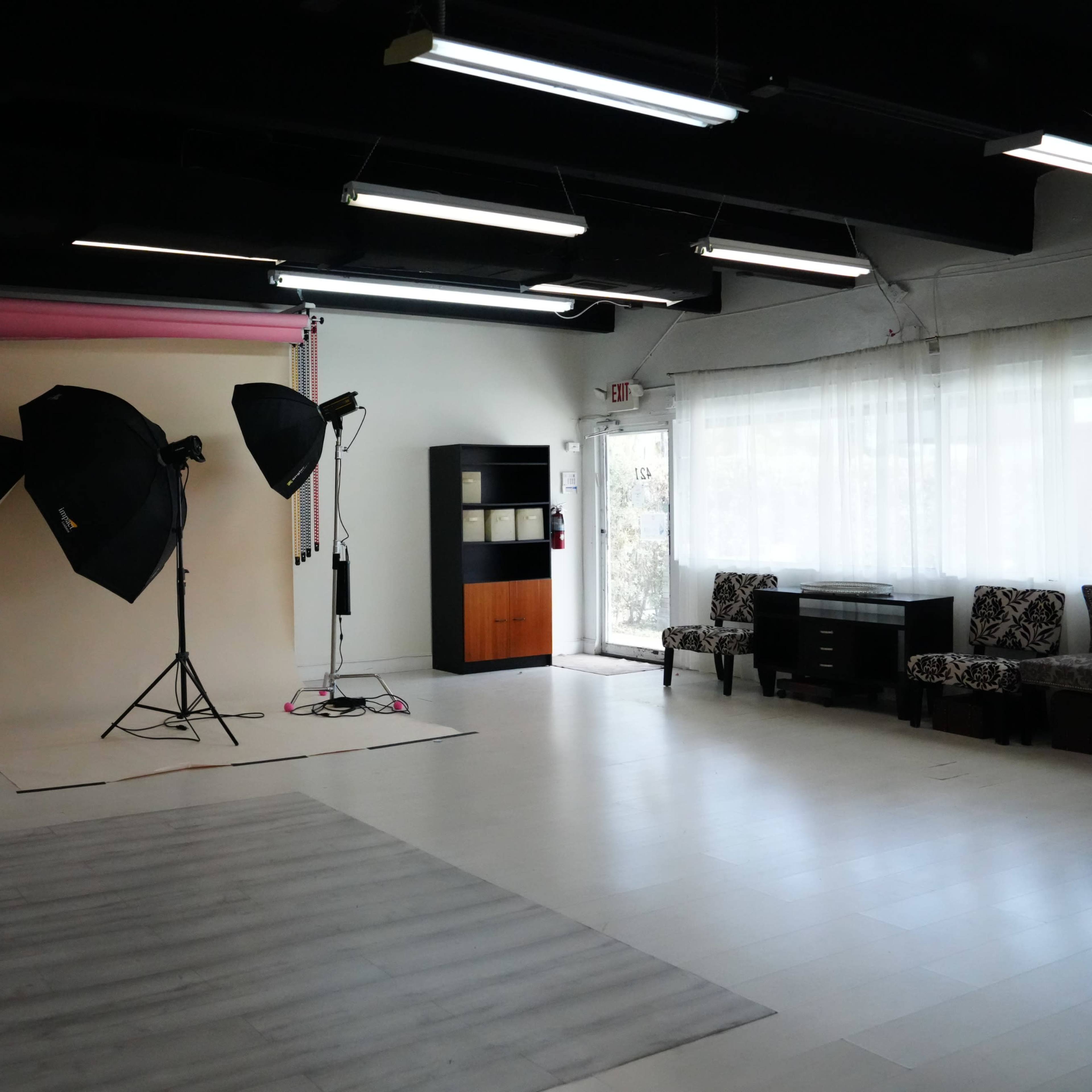 A photography studio with a backdrop, lighting equipment, and a seating area.