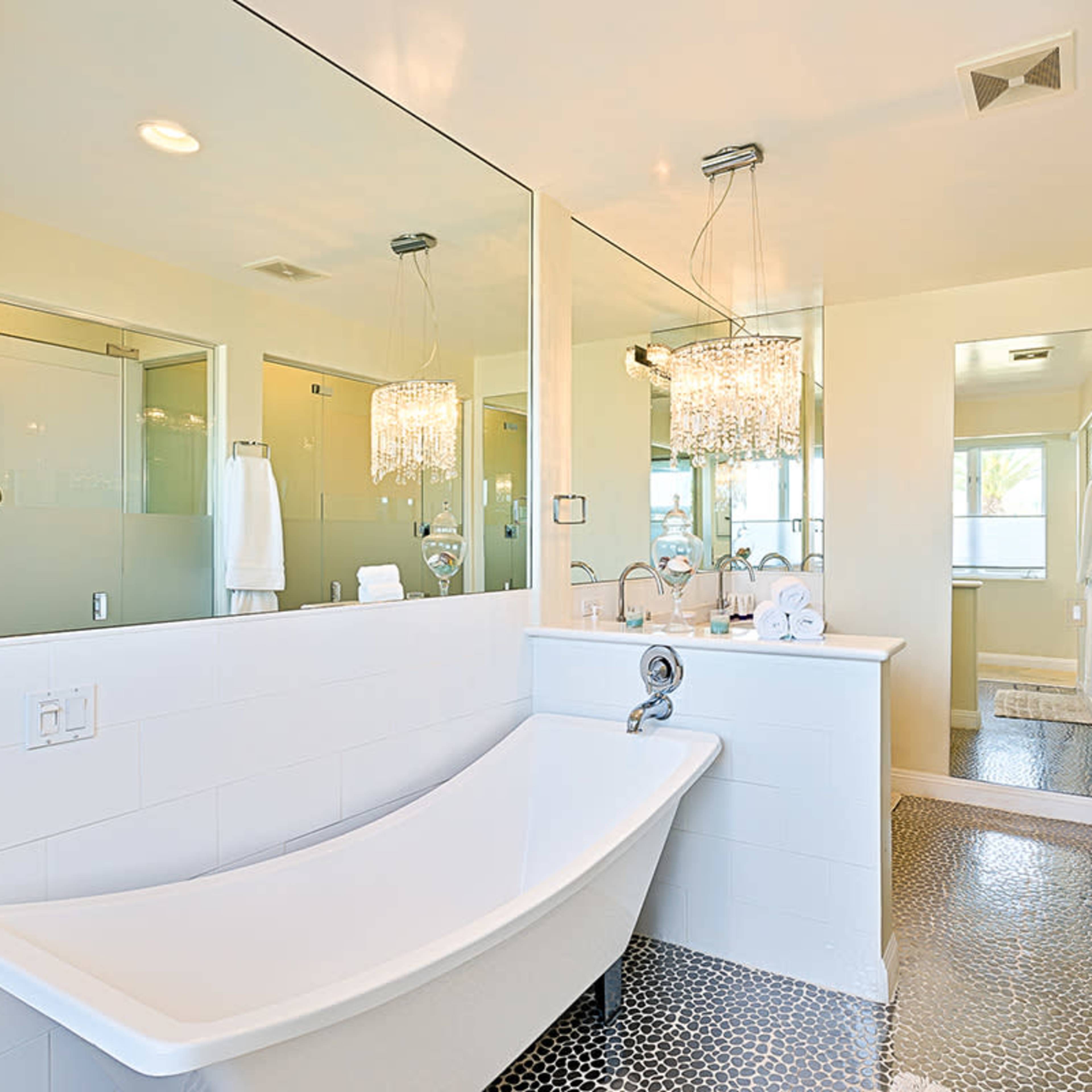 A modern bathroom featuring a freestanding bathtub, dual sinks with a large mirror, and a glass shower enclosure.