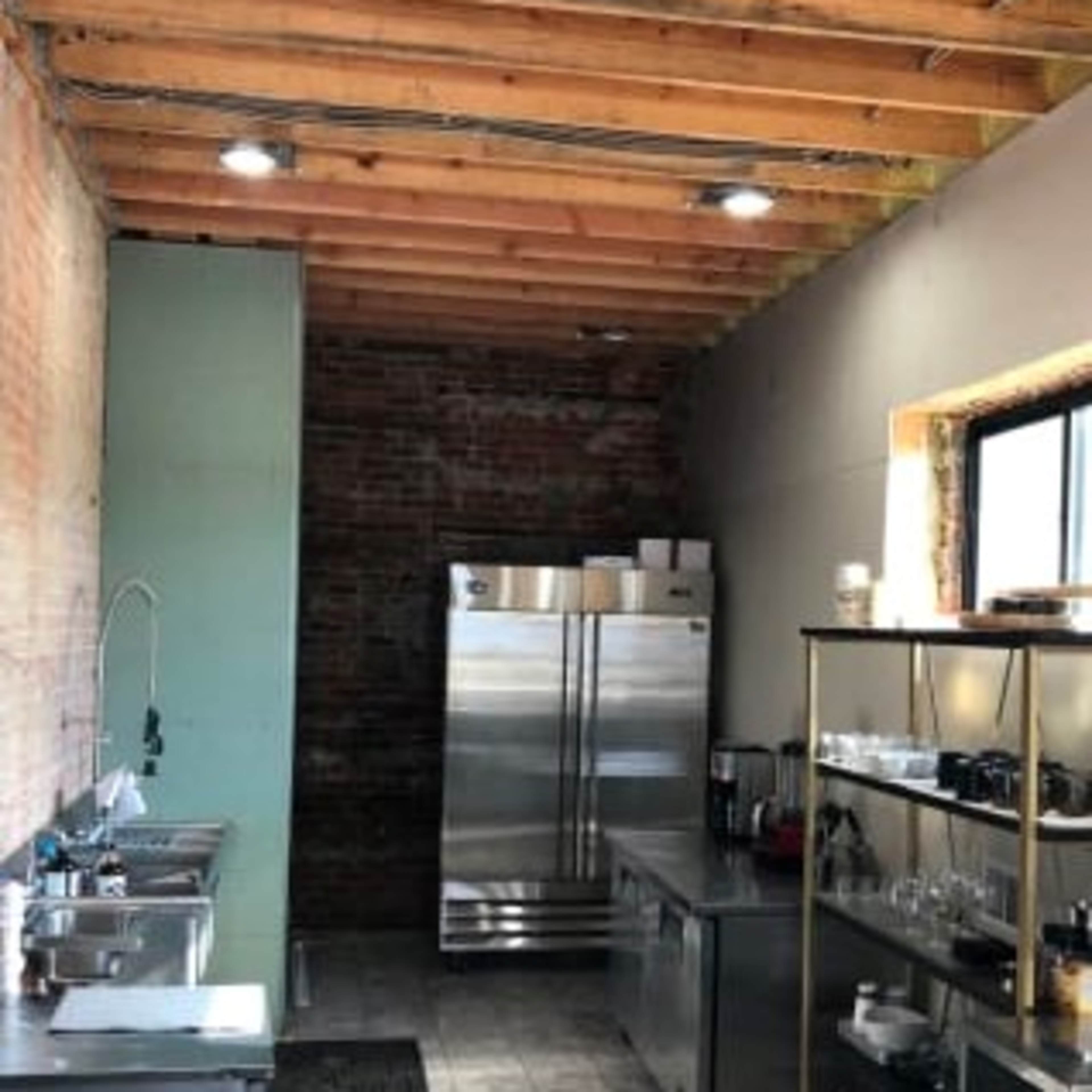 The kitchen features stainless steel appliances, a tiled floor, and exposed wooden beams in the ceiling.
