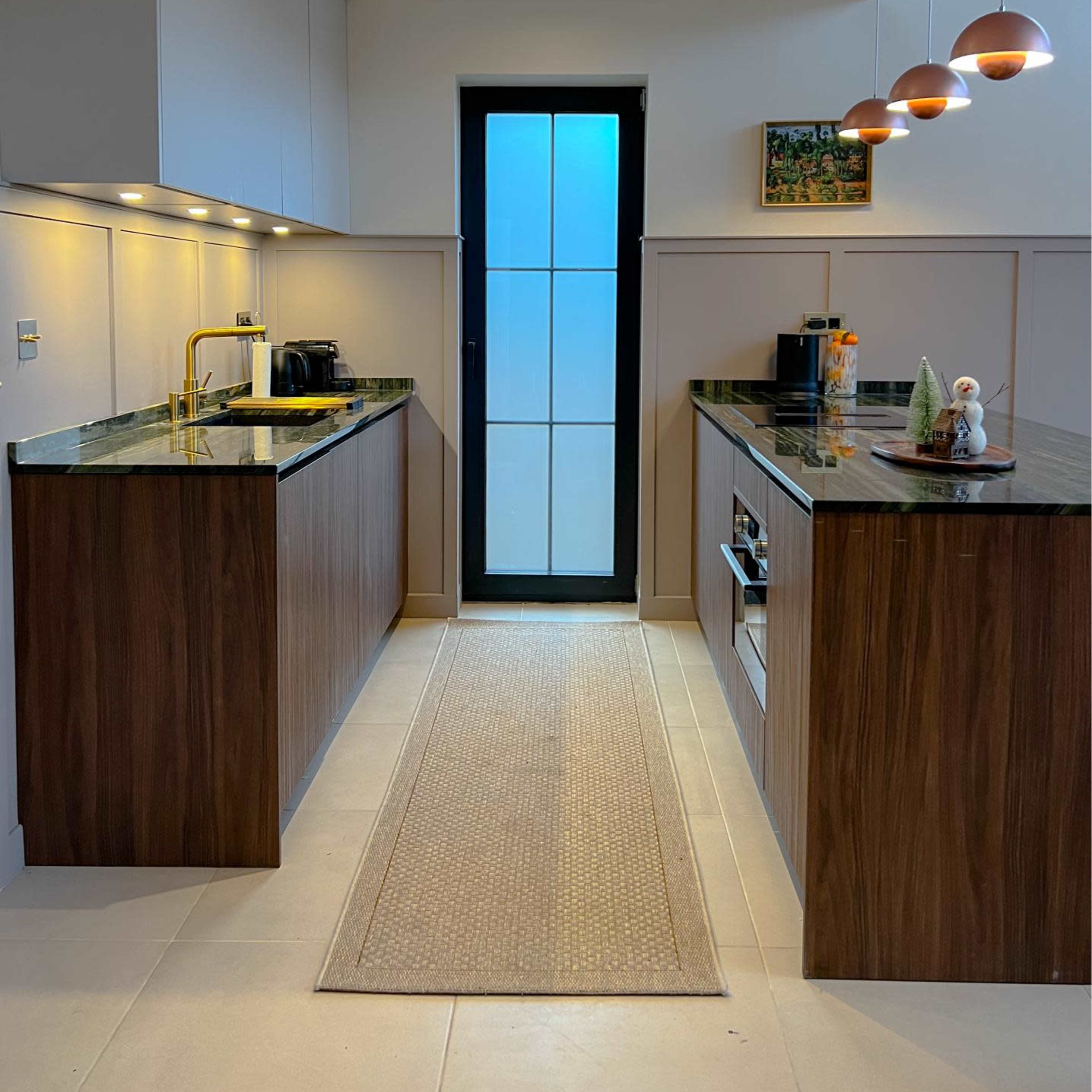 A modern kitchen features dark wood cabinetry, a marble countertop, and a door with glass panels leading to the outside.
