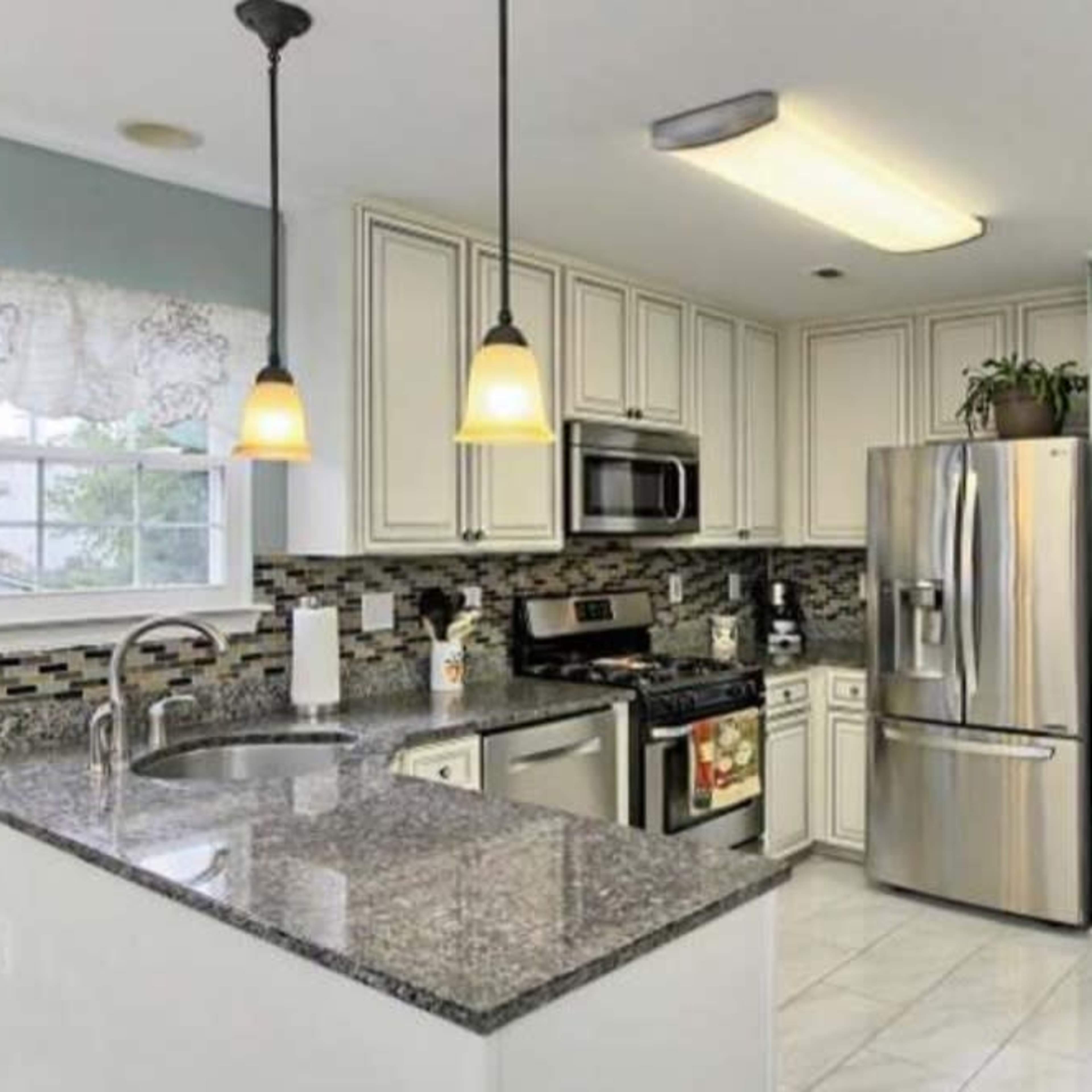 A kitchen with white cabinets, stainless steel appliances, and dark granite countertops.