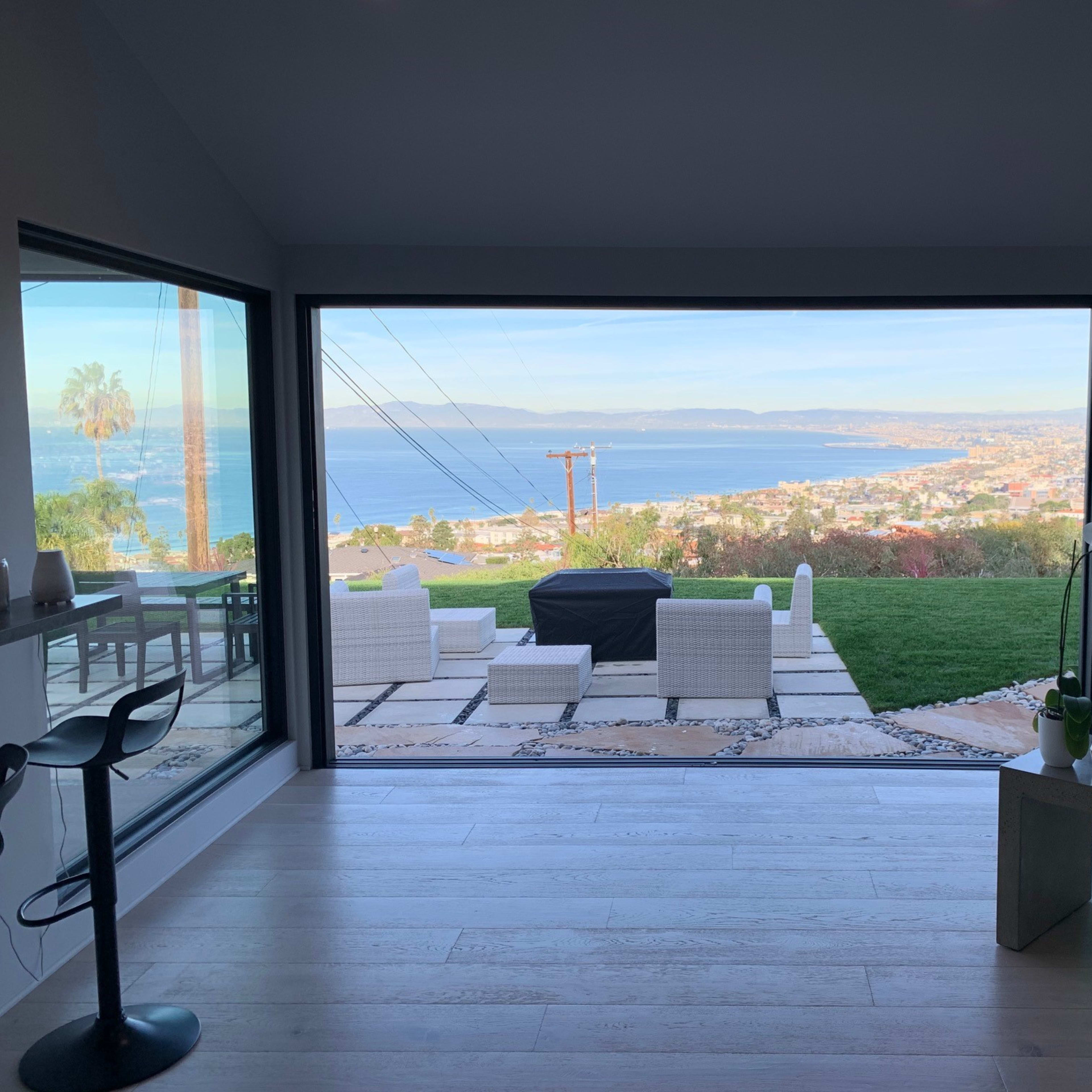 A modern interior space with large glass windows overlooking a coastal landscape and city.