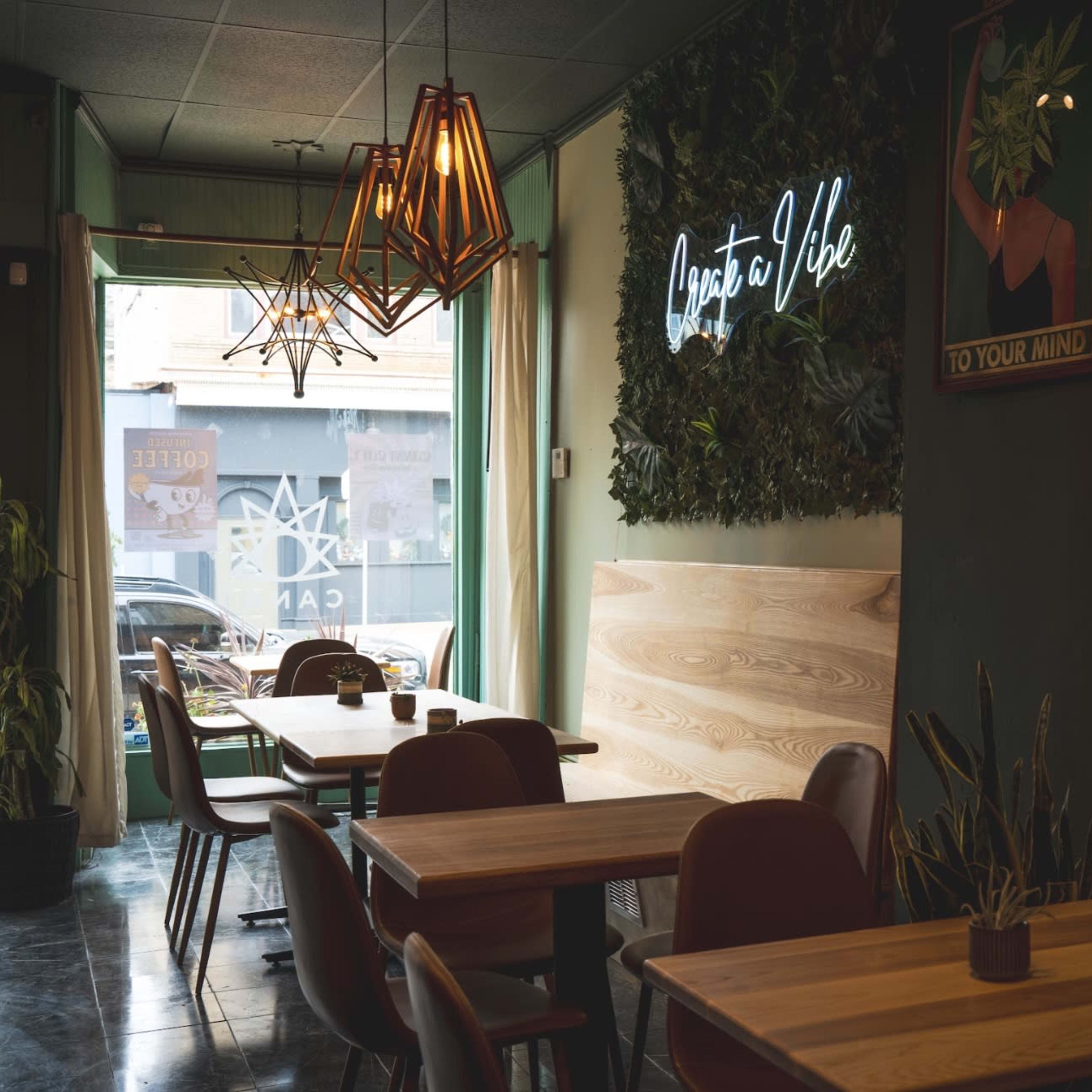 A cozy café interior with wooden tables, green walls, and decorative lighting.