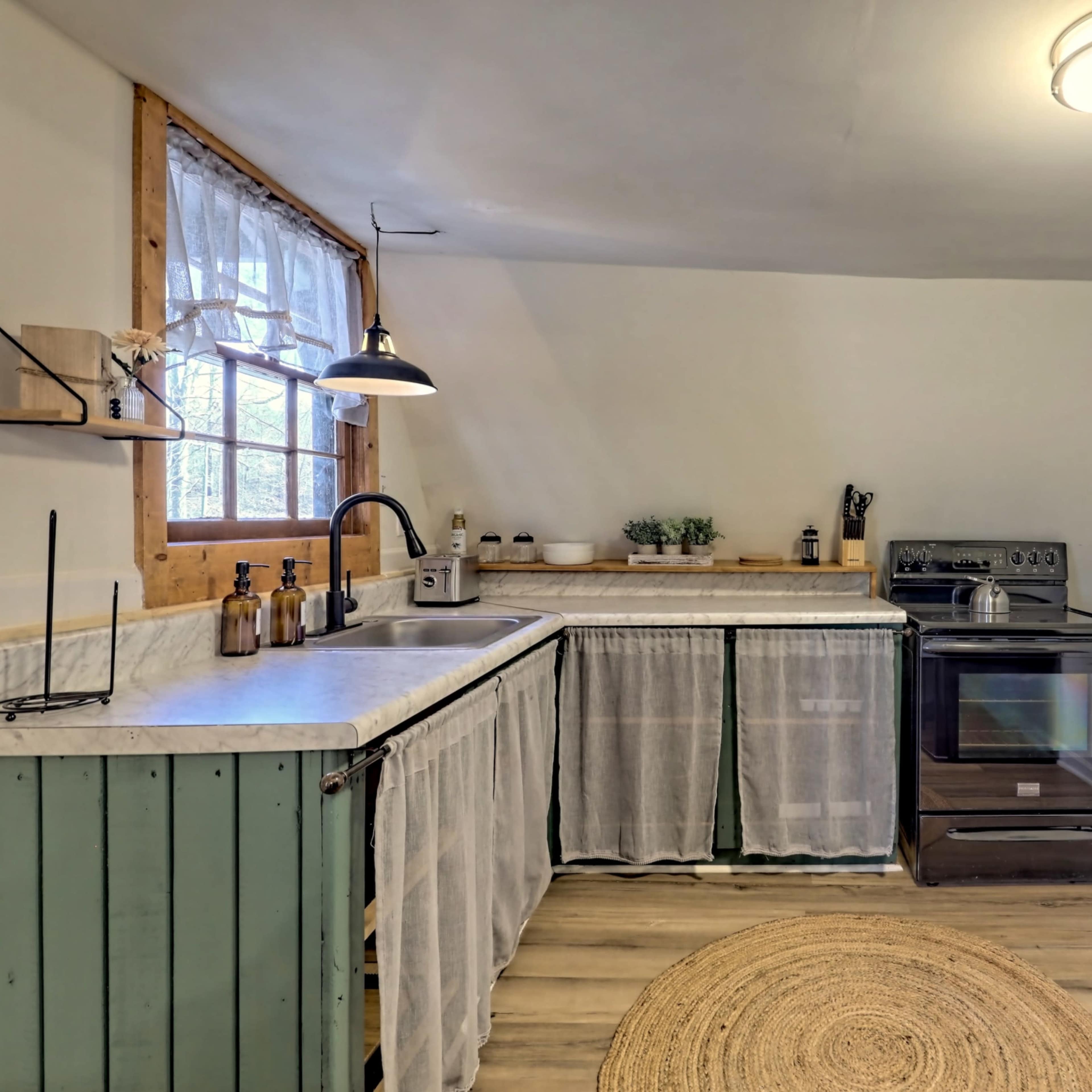 A small kitchen with a wooden countertop, an oven, and a retro-style refrigerator, complemented by a round rug on the floor.