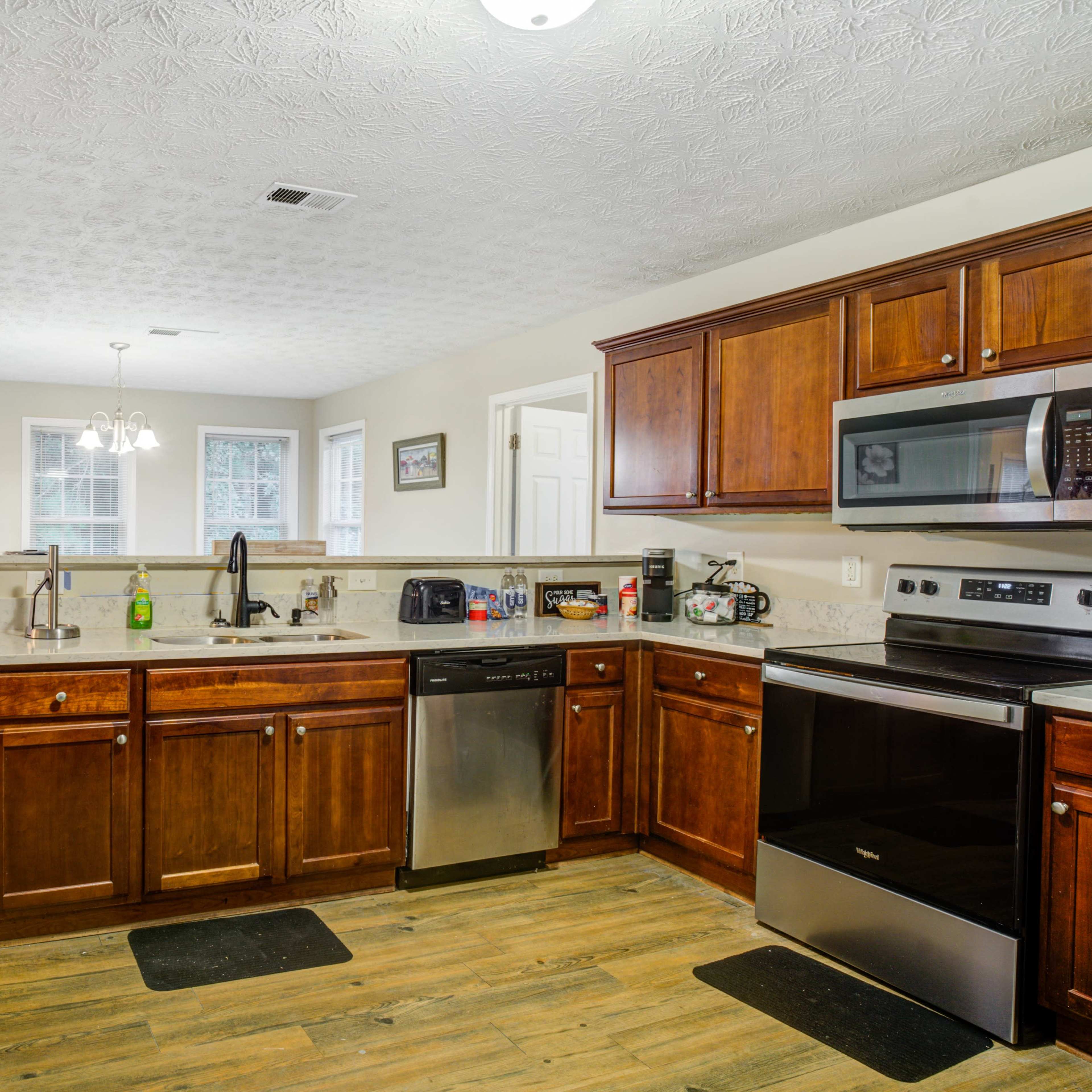 A spacious kitchen with wooden cabinets, stainless steel appliances, and a light-colored wall.
