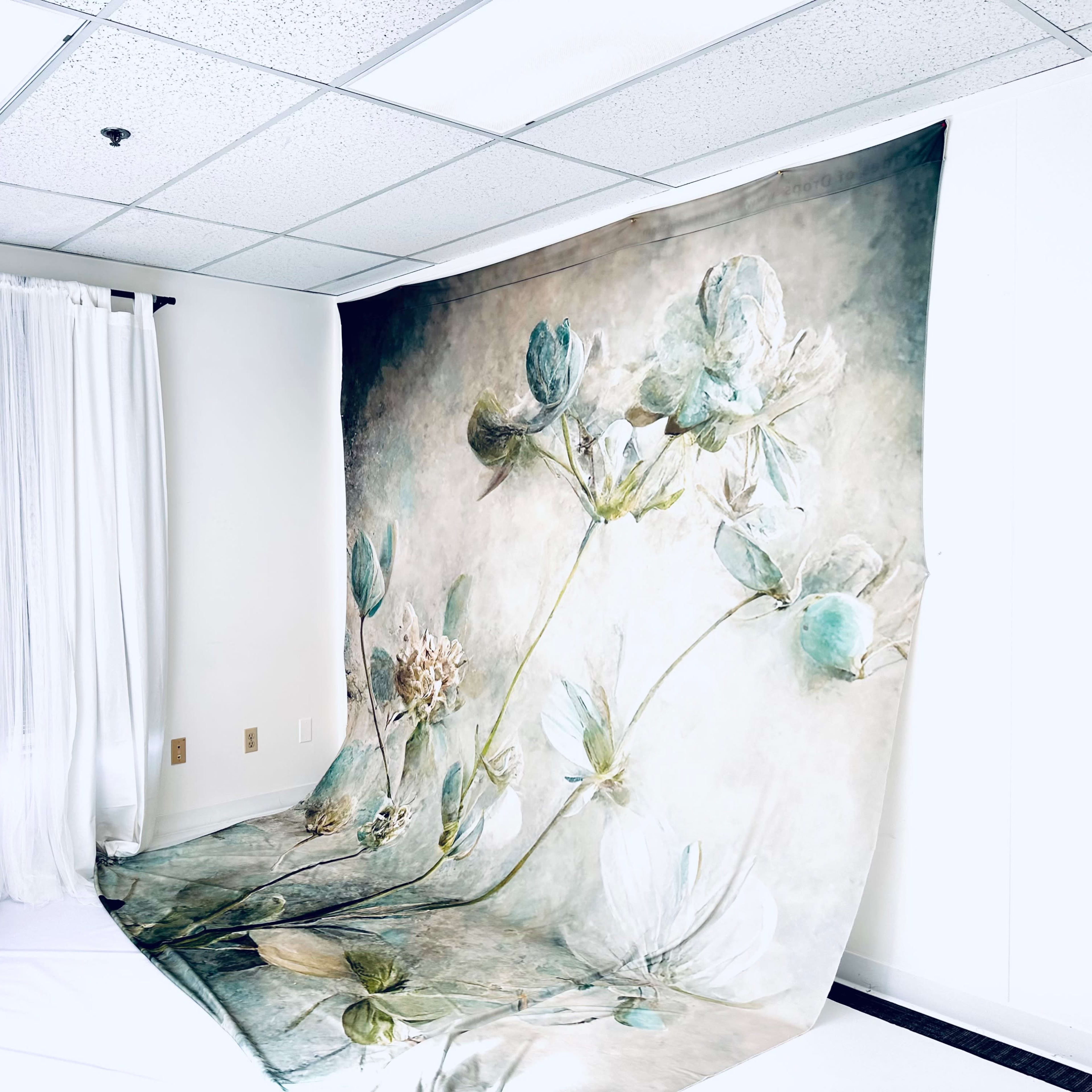 A large floral backdrop is displayed in a bright room with sheer curtains and a white floor.