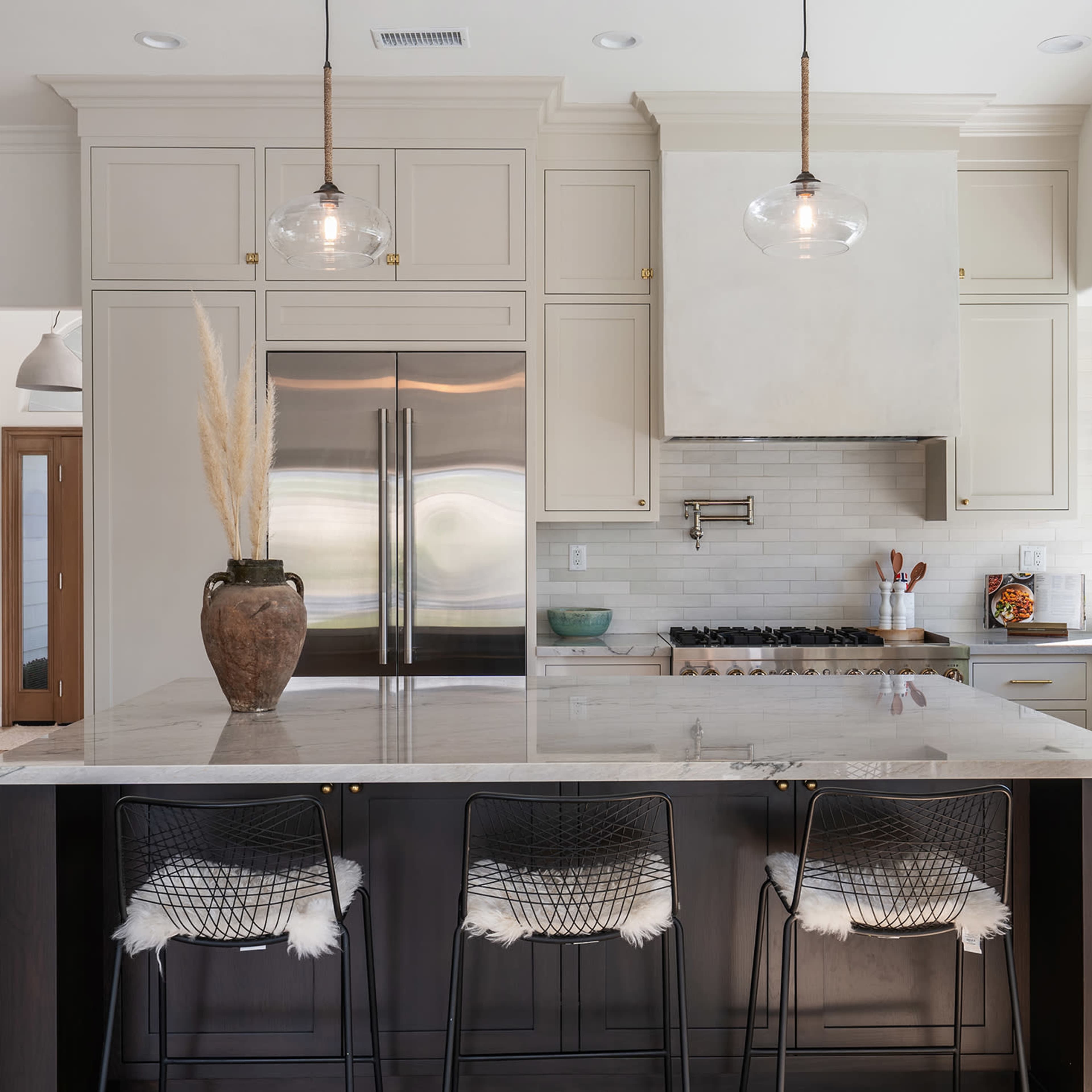 A modern kitchen features a large island with seating, sleek cabinetry, and stainless steel appliances.