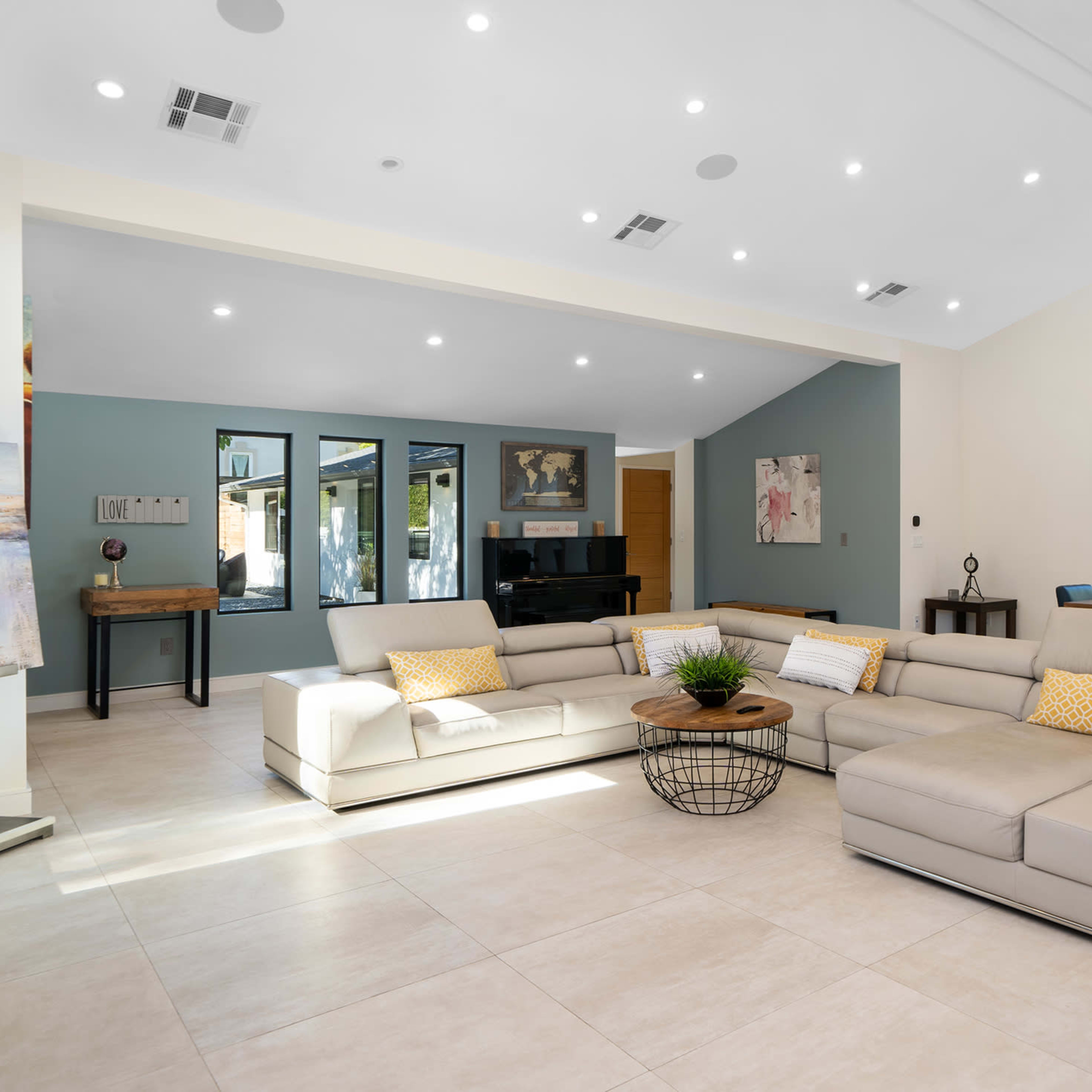 A spacious living area featuring a large sectional sofa, a dining table, and large windows that allow natural light to illuminate the space.