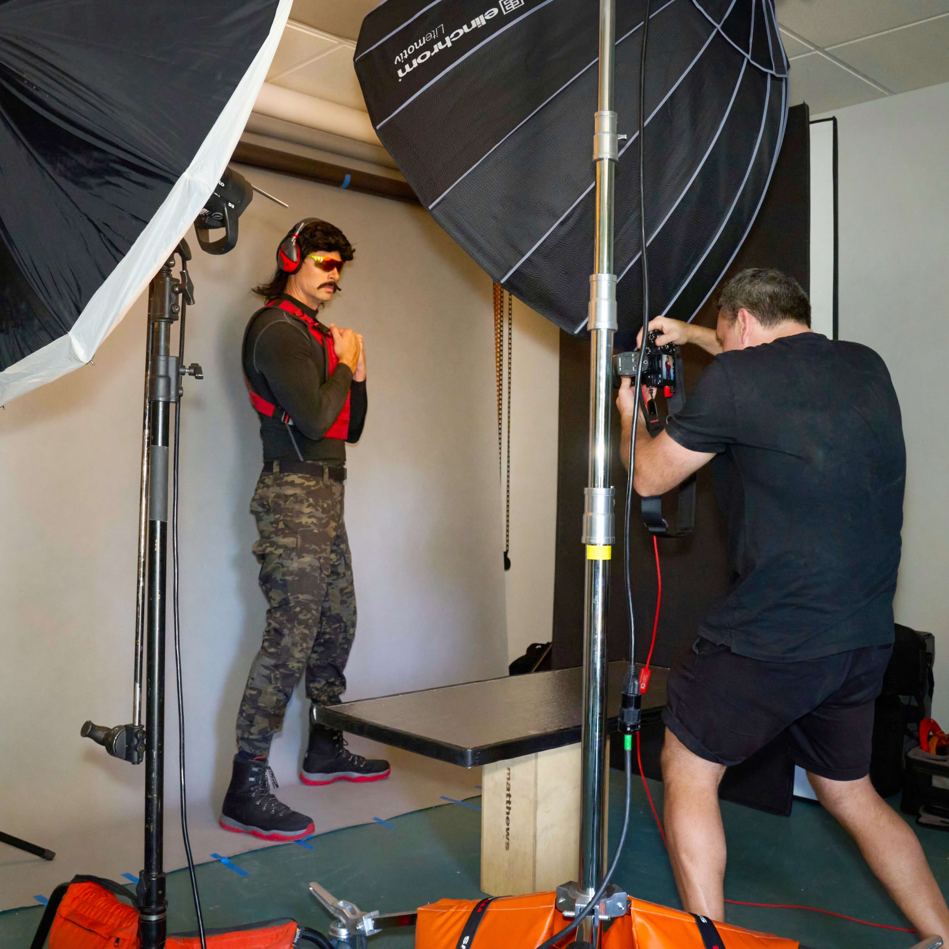 A photographer captures images of a model posing in a studio setup with multiple light sources.