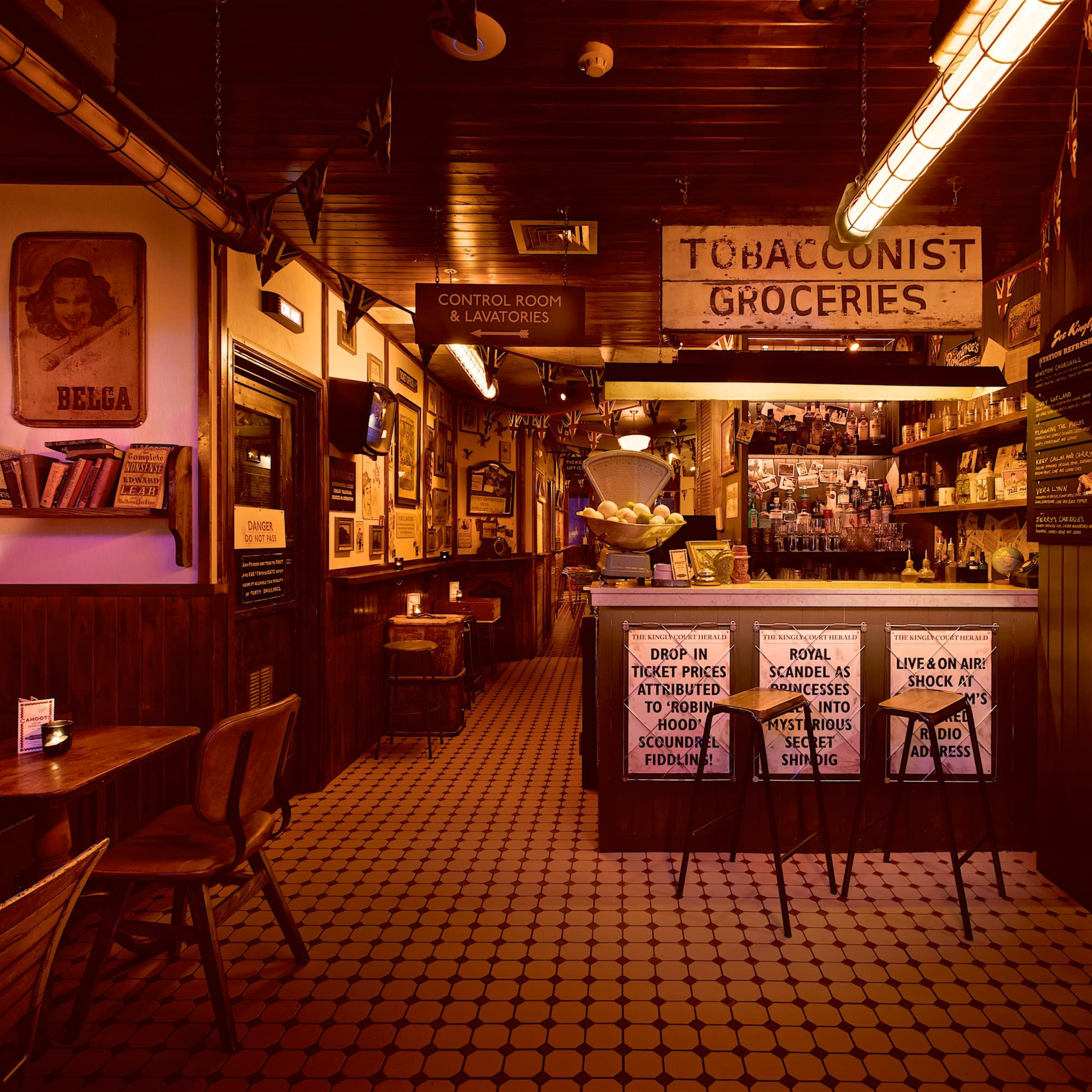 A vintage-style bar with wooden walls, a counter displaying various items, and tables in a warmly lit atmosphere.