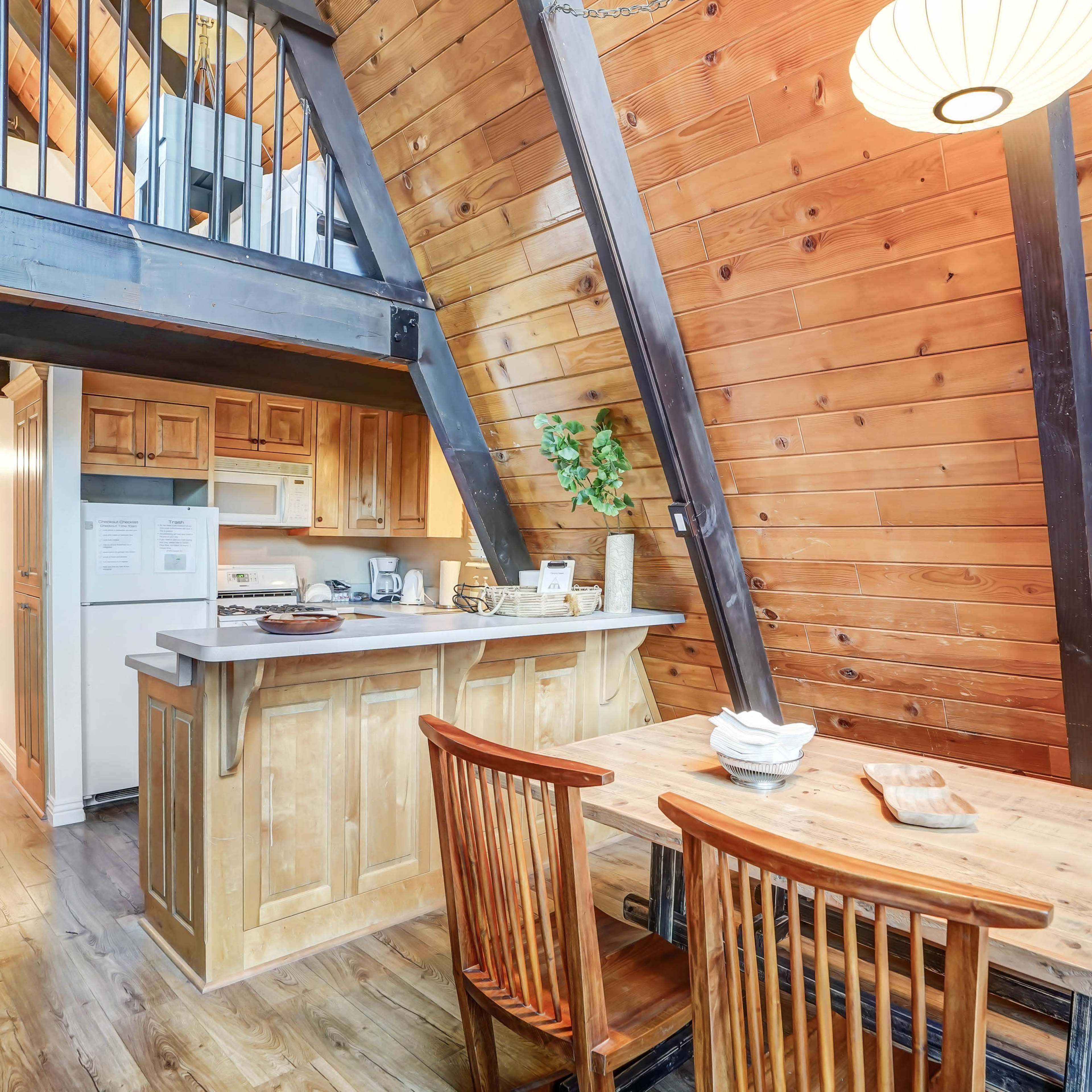 The interior of a cabin features wooden walls, a dining table with chairs, and a kitchen area visible in the background.