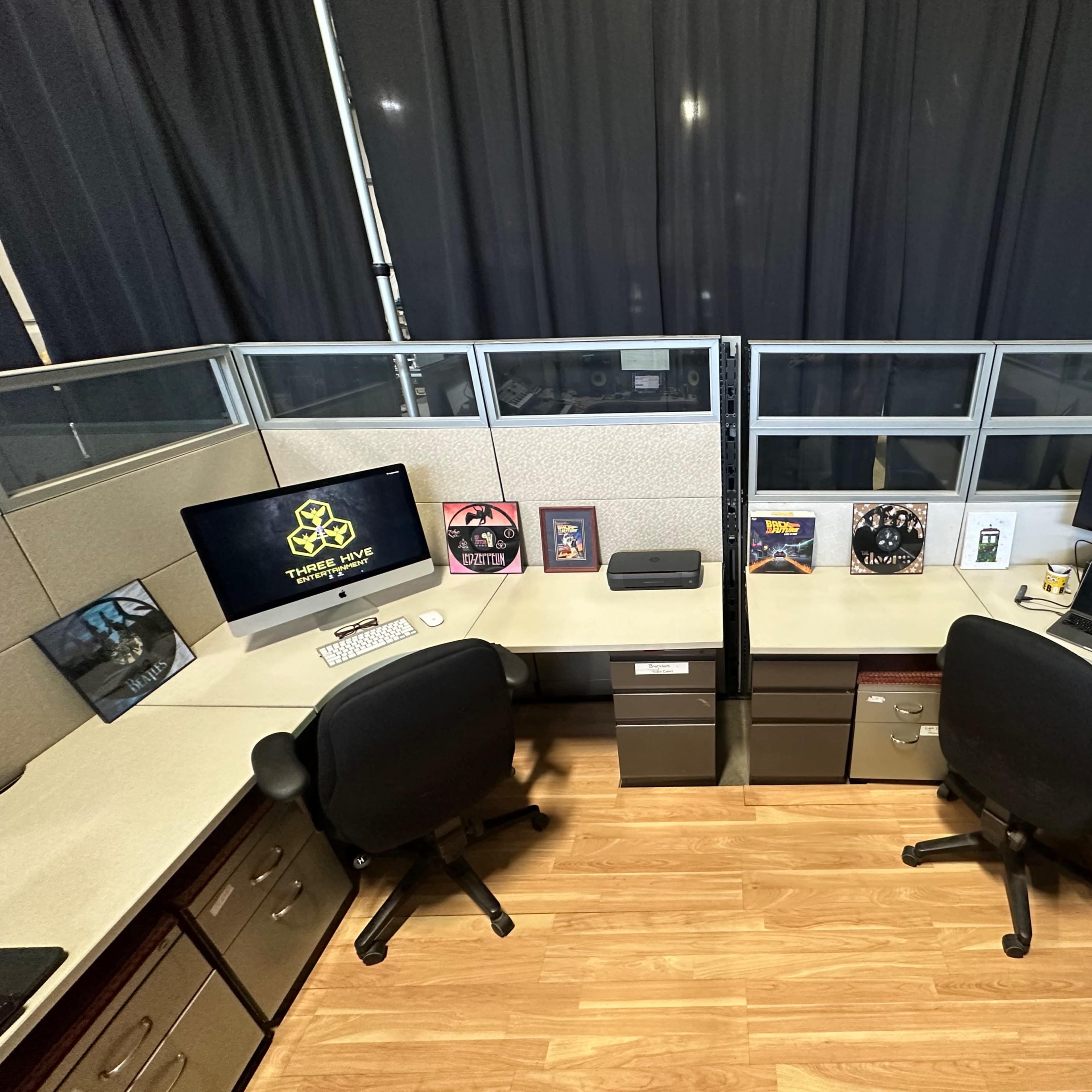Two office workstations separated by a partition, each equipped with monitors and decorative items on the desks.