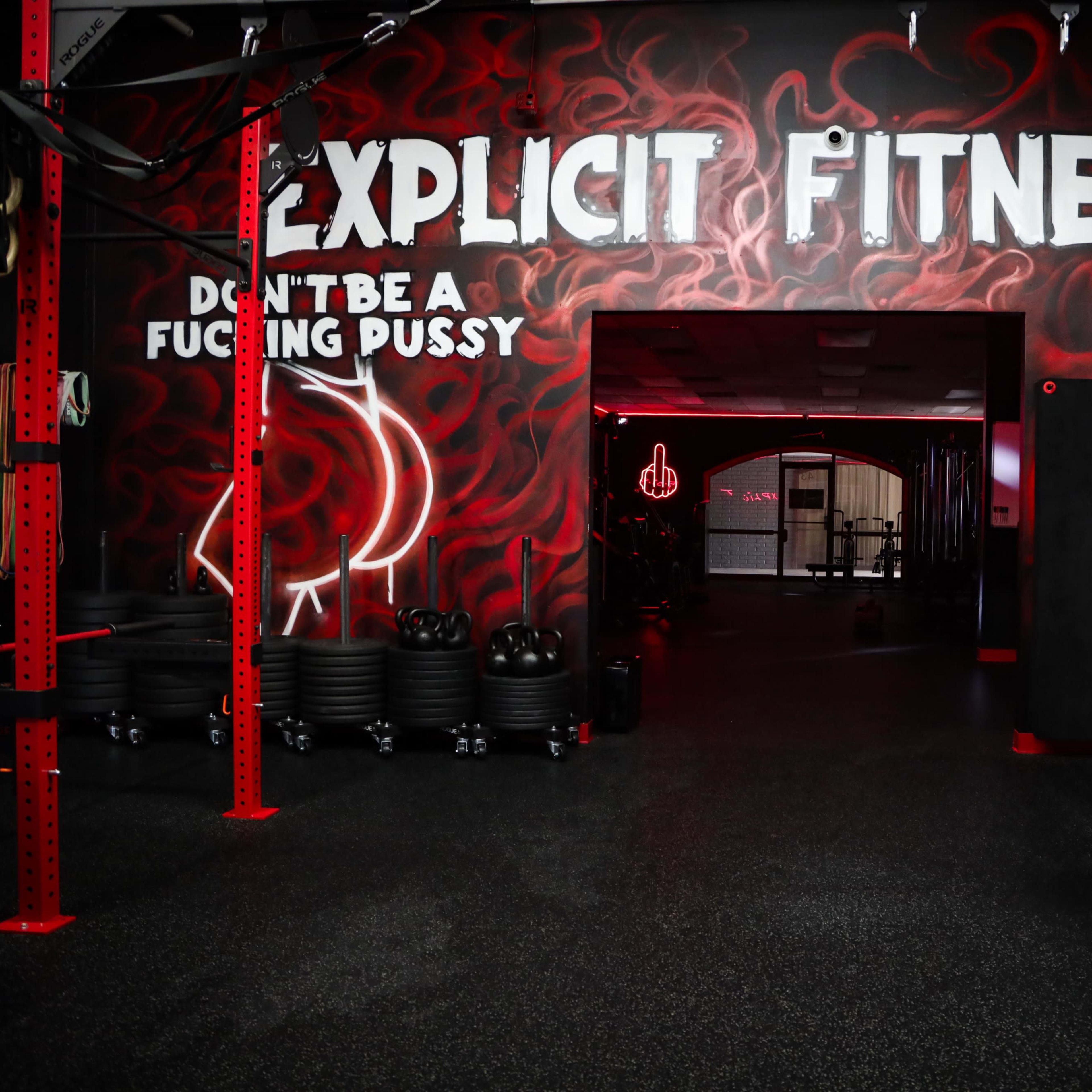 The entrance to a gym with a striking red and black mural on the wall that features bold text and a graphic design.
