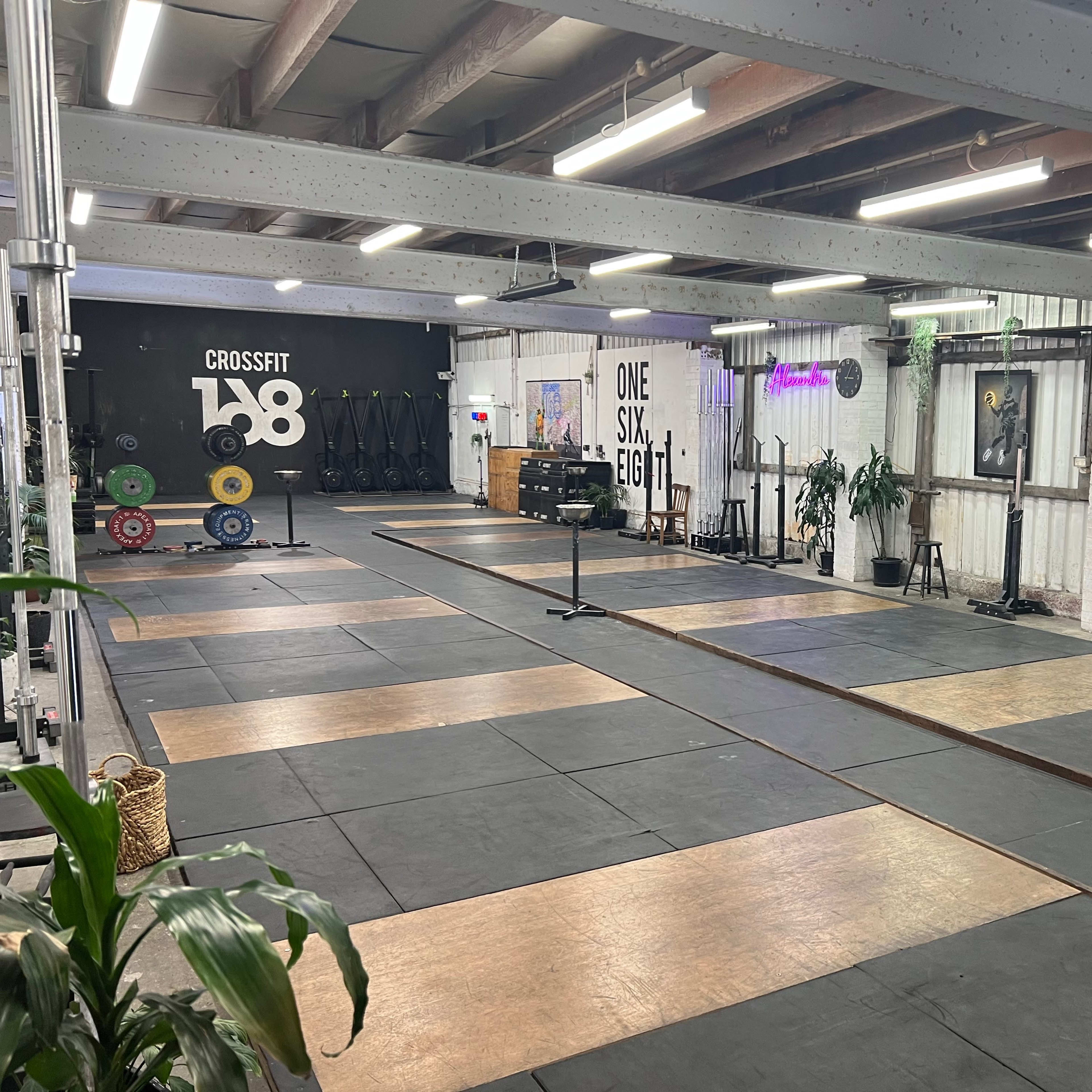 A CrossFit gym with designated lifting areas, weight plates, and equipment arranged neatly on a rubber floor.
