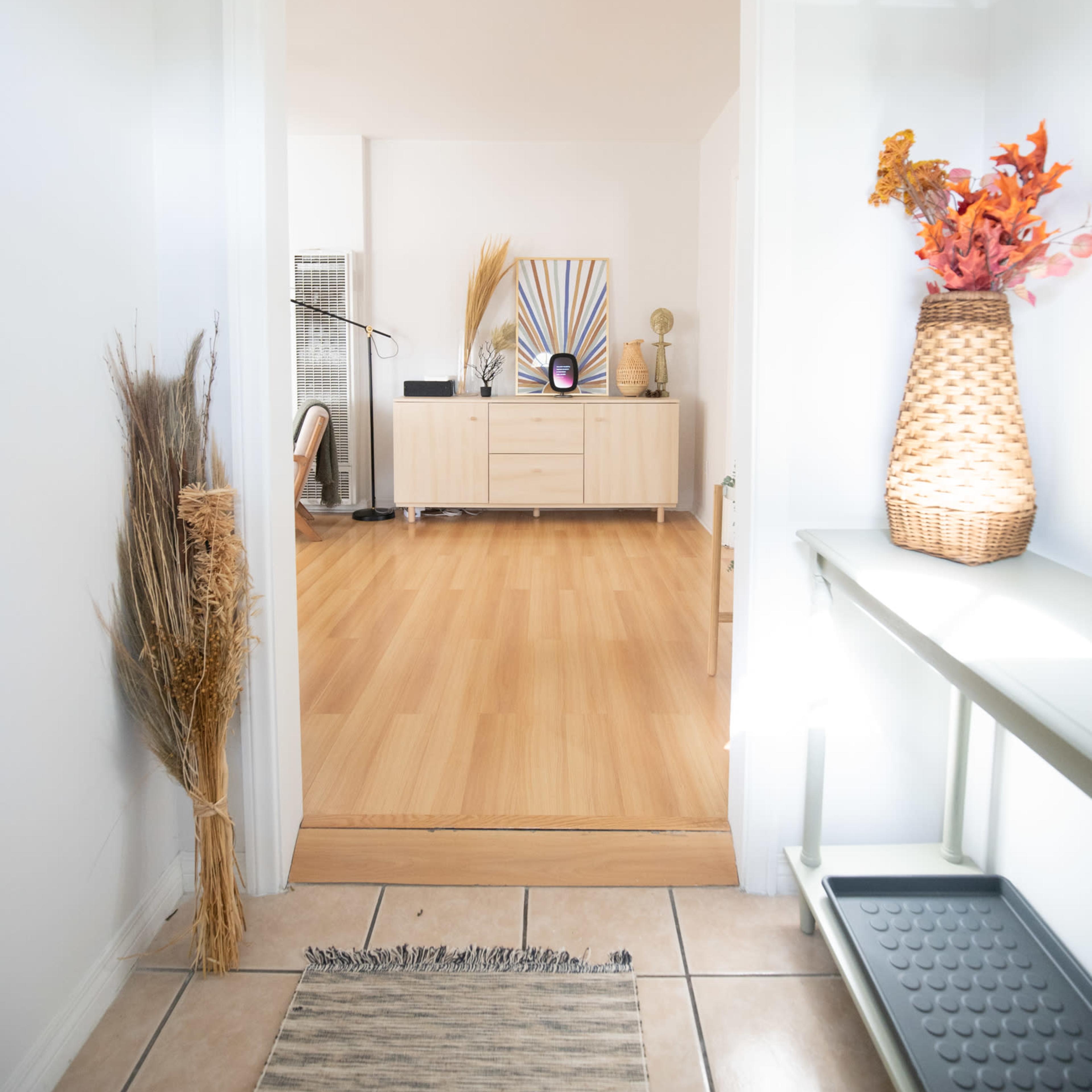 A hallway leads to a living area featuring a light-colored wooden floor and a decorative console table.
