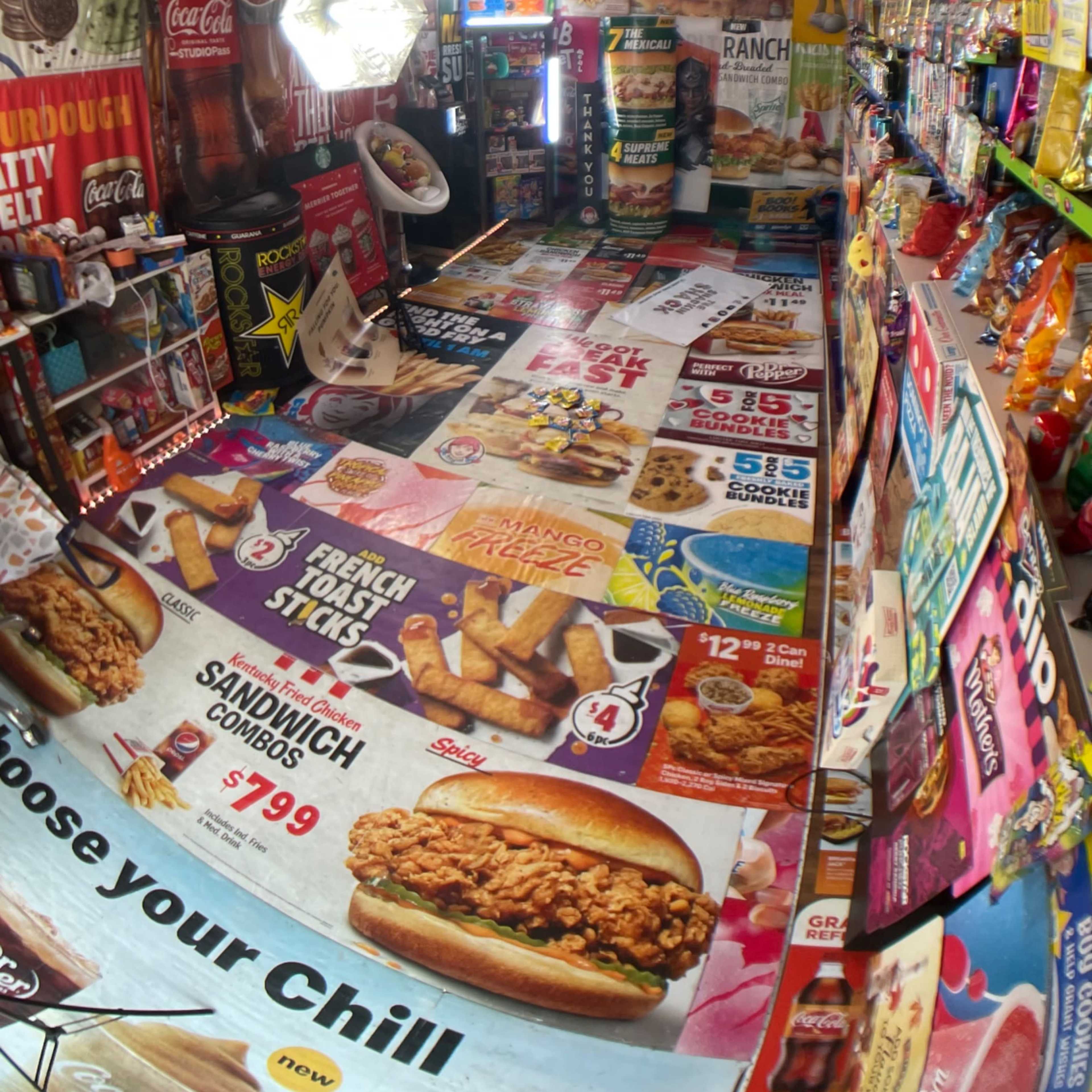 An indoor space filled with colorful food advertisements and snack items on shelves, creating a vibrant, cluttered atmosphere.