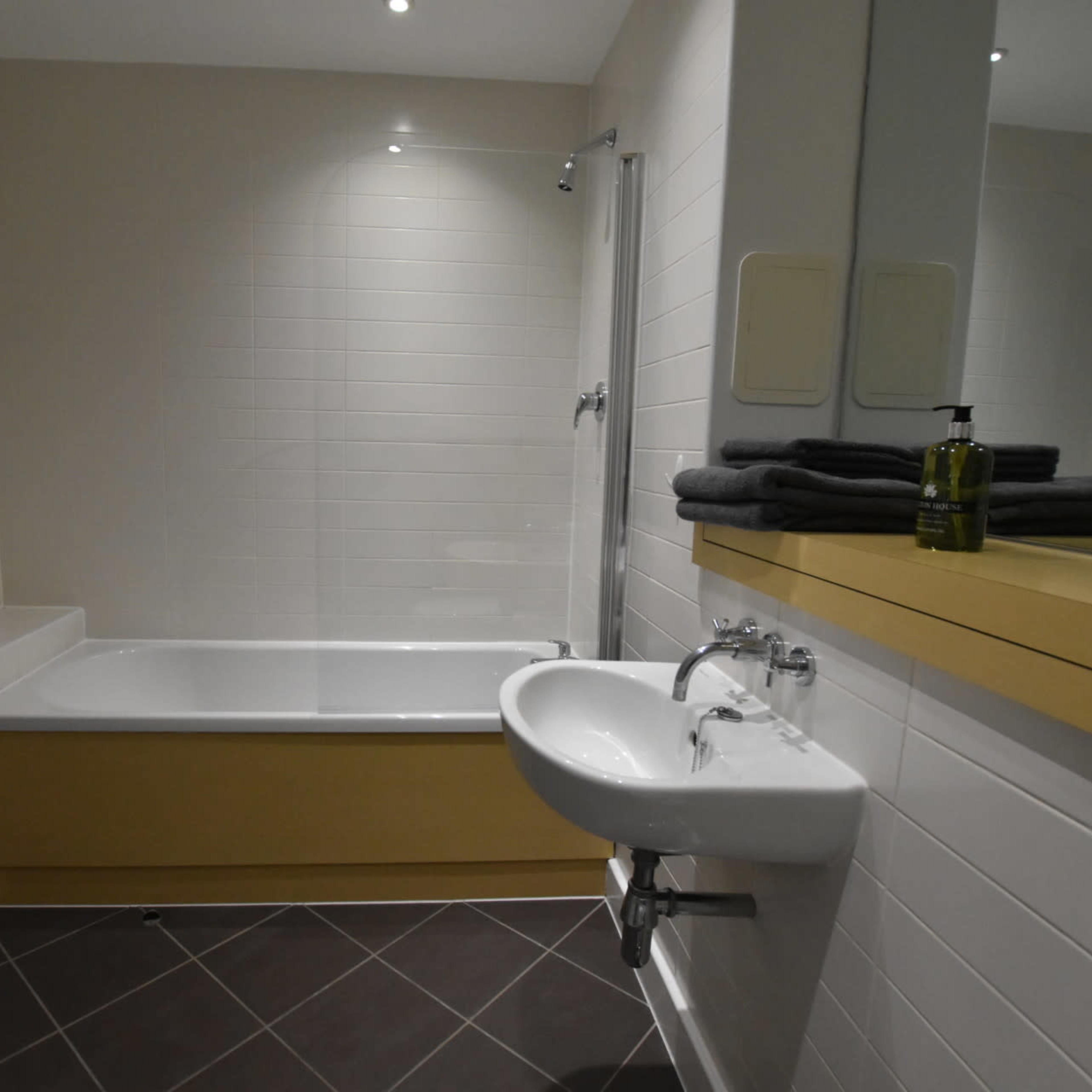 A bathroom equipped with a bathtub, a shower, a sink, and neatly arranged towels on a countertop.