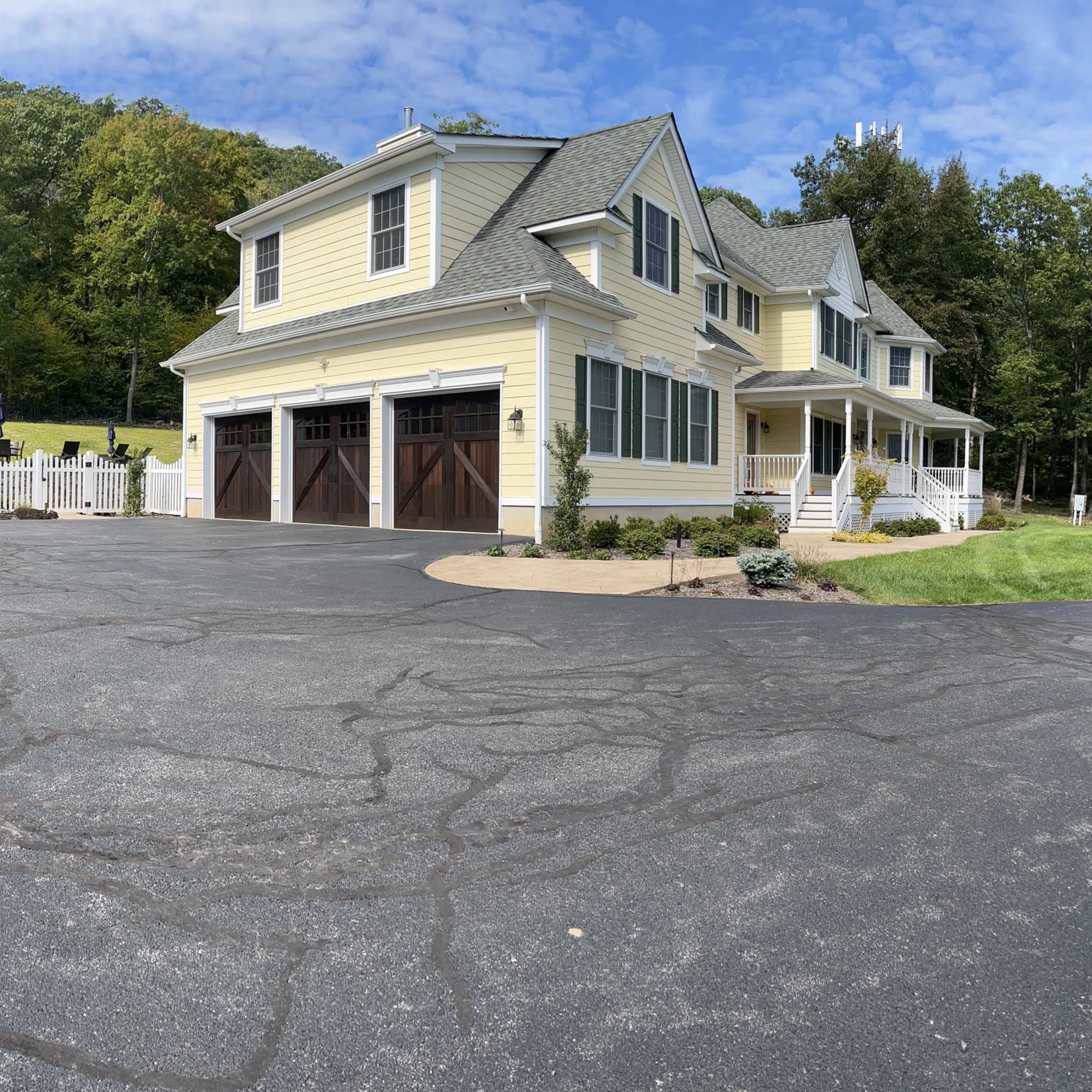 A spacious residential property features a large yellow house with a garage and an adjacent outbuilding set in a landscaped area.