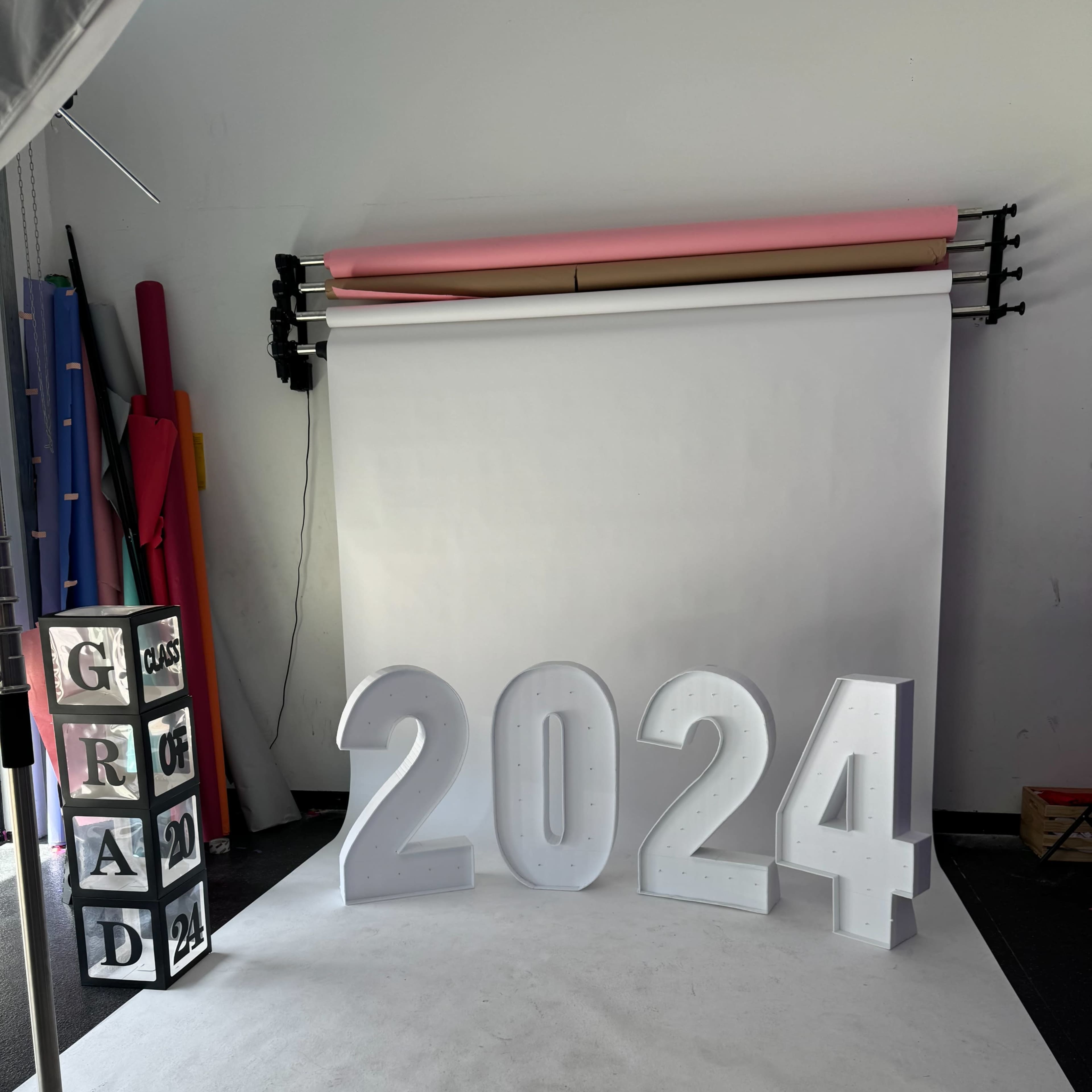 Large illuminated numbers forming "2024" set against a plain backdrop in a photography studio.
