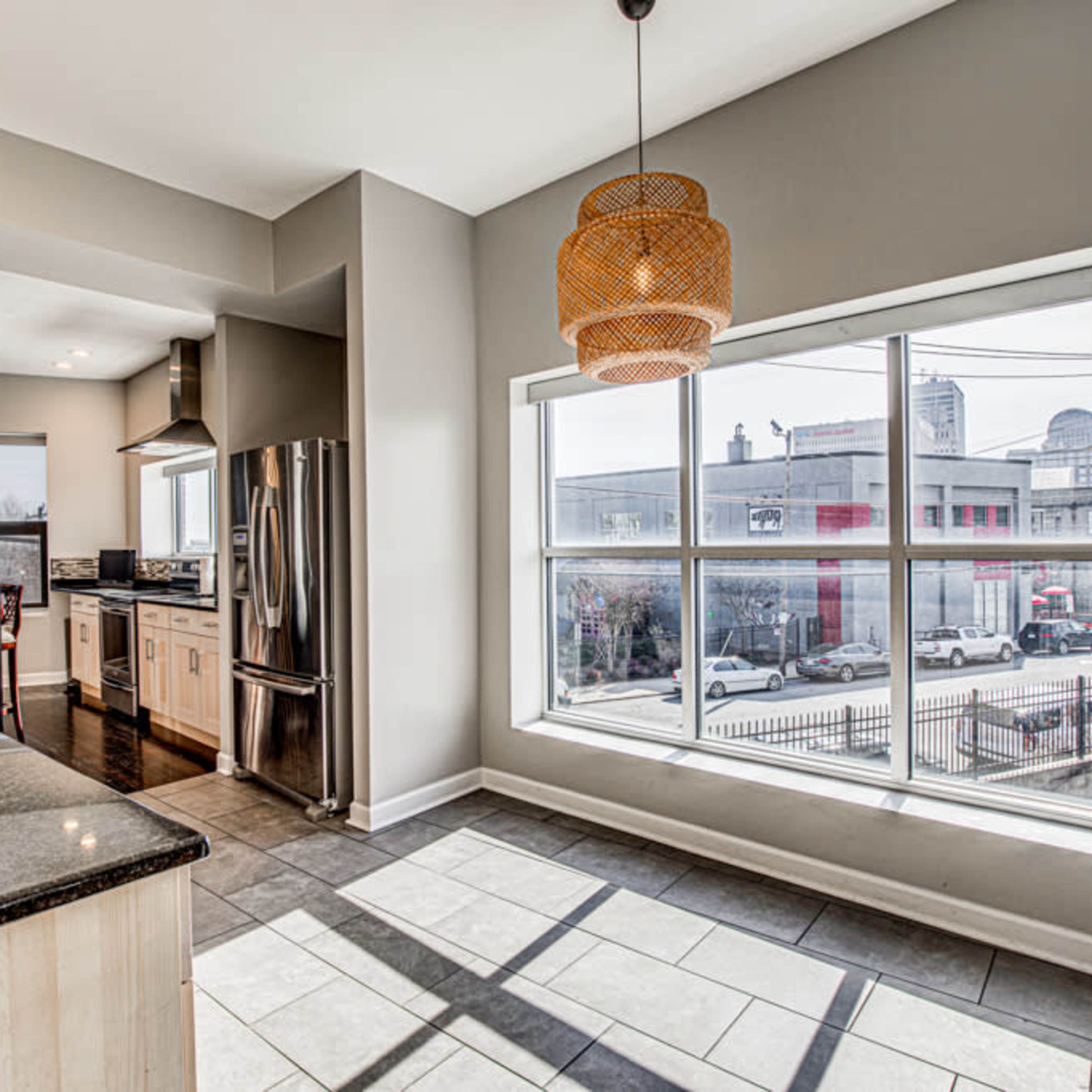 A modern kitchen with gray walls, a large window, and stainless steel appliances.