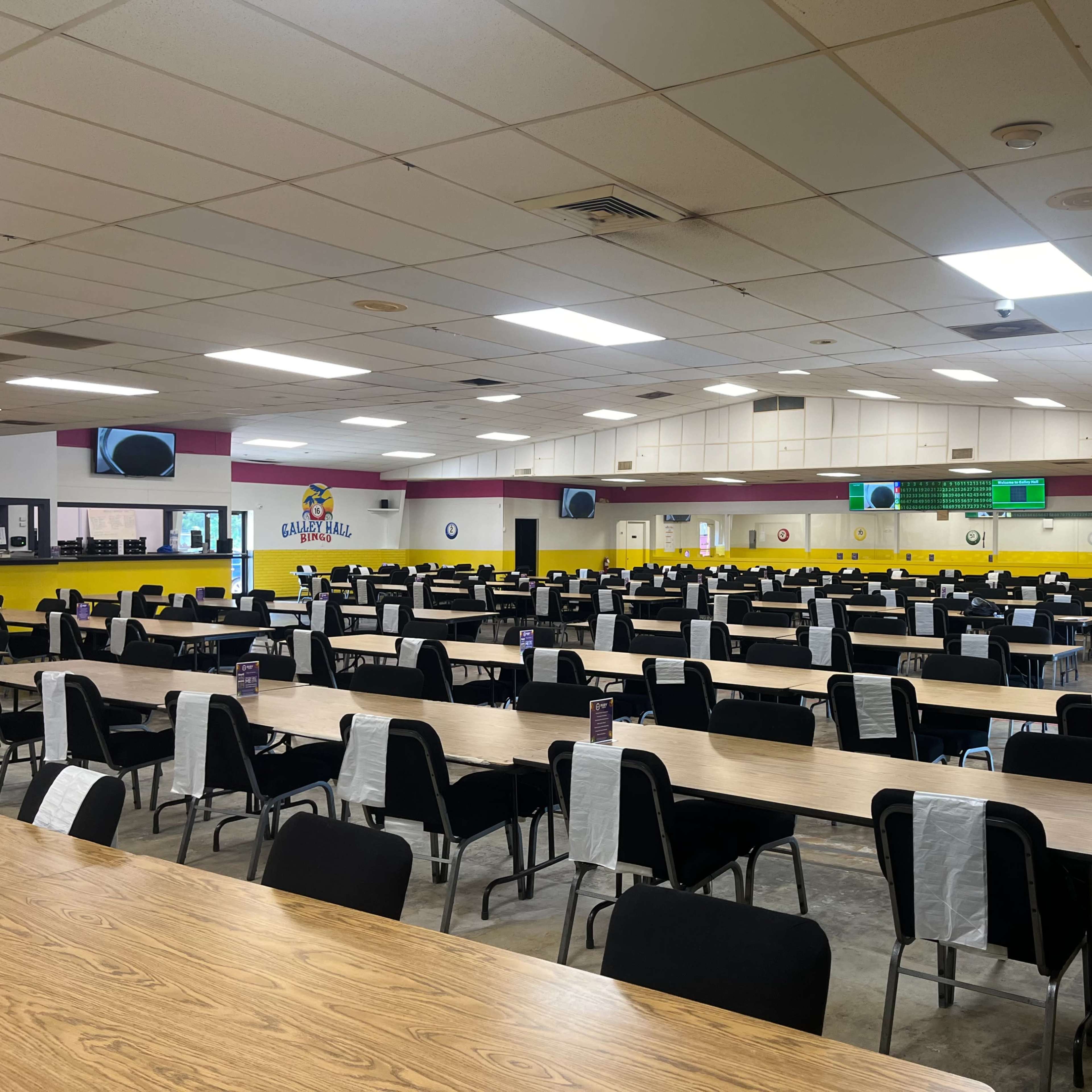 A large, empty cafeteria with many rows of tables and chairs arranged throughout the space.