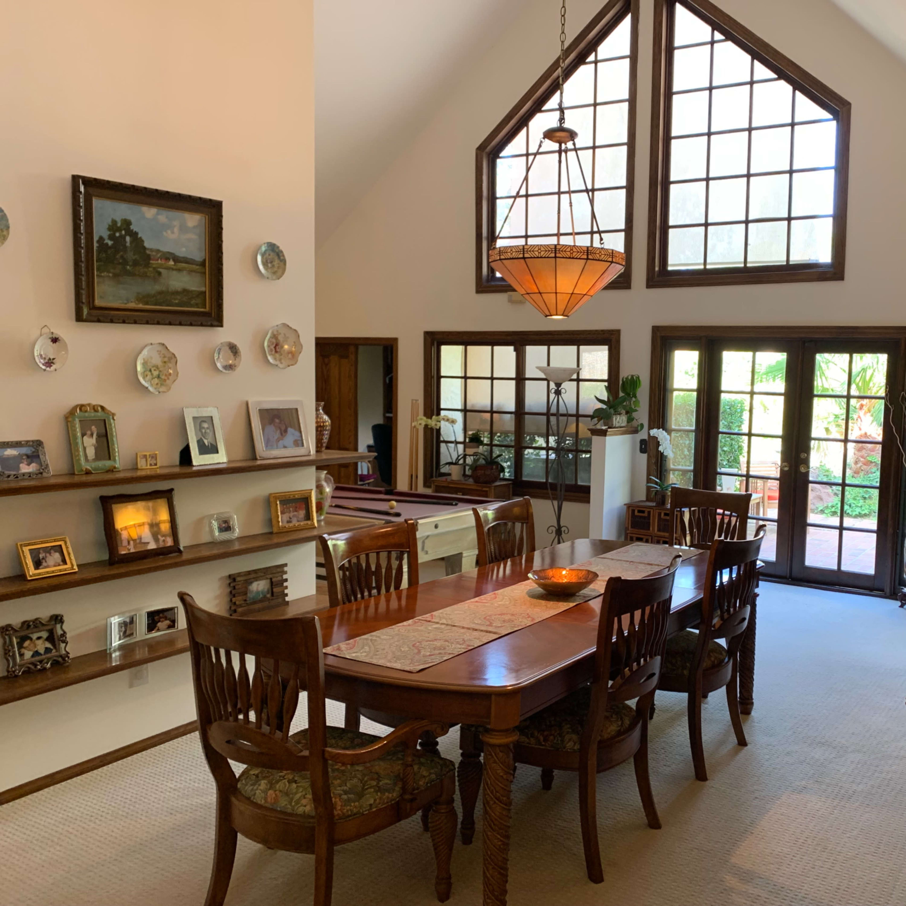 A dining area with a wooden table, chairs, and a large window that allows natural light to illuminate the space.