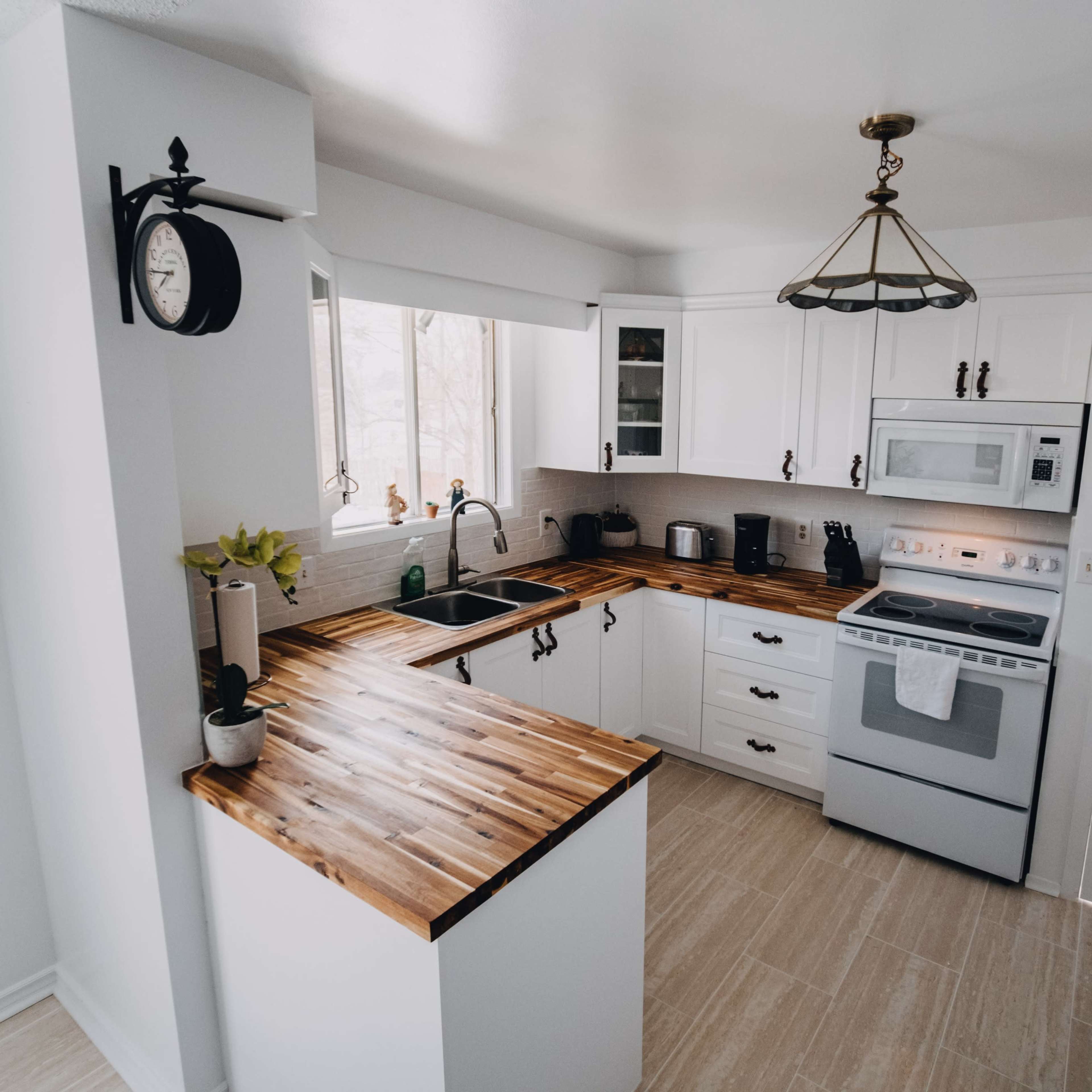 A modern kitchen with wooden countertops, white cabinets, and stainless steel appliances.