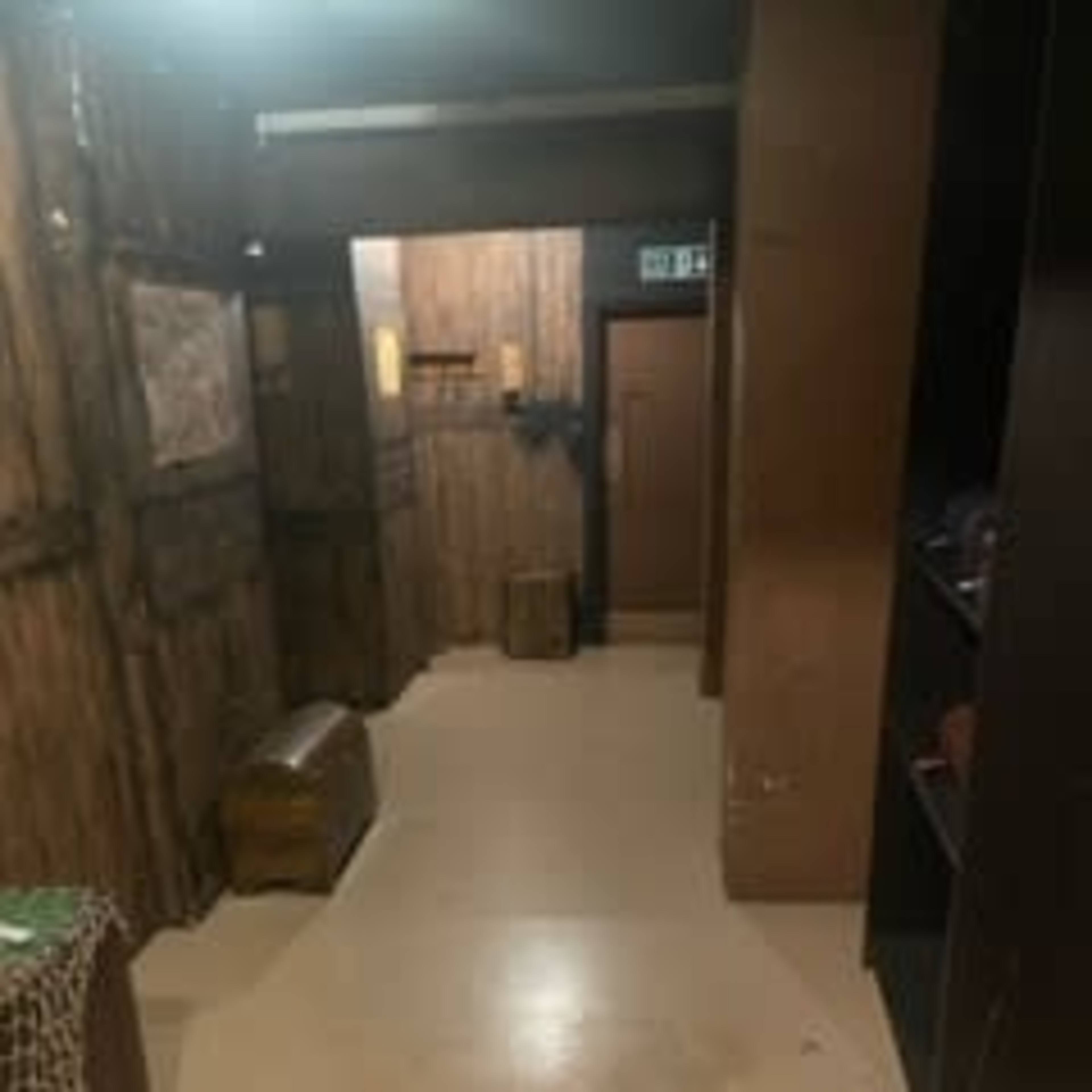 A narrow hallway with wooden walls, a door at the end, and a couple of boxes on the floor.