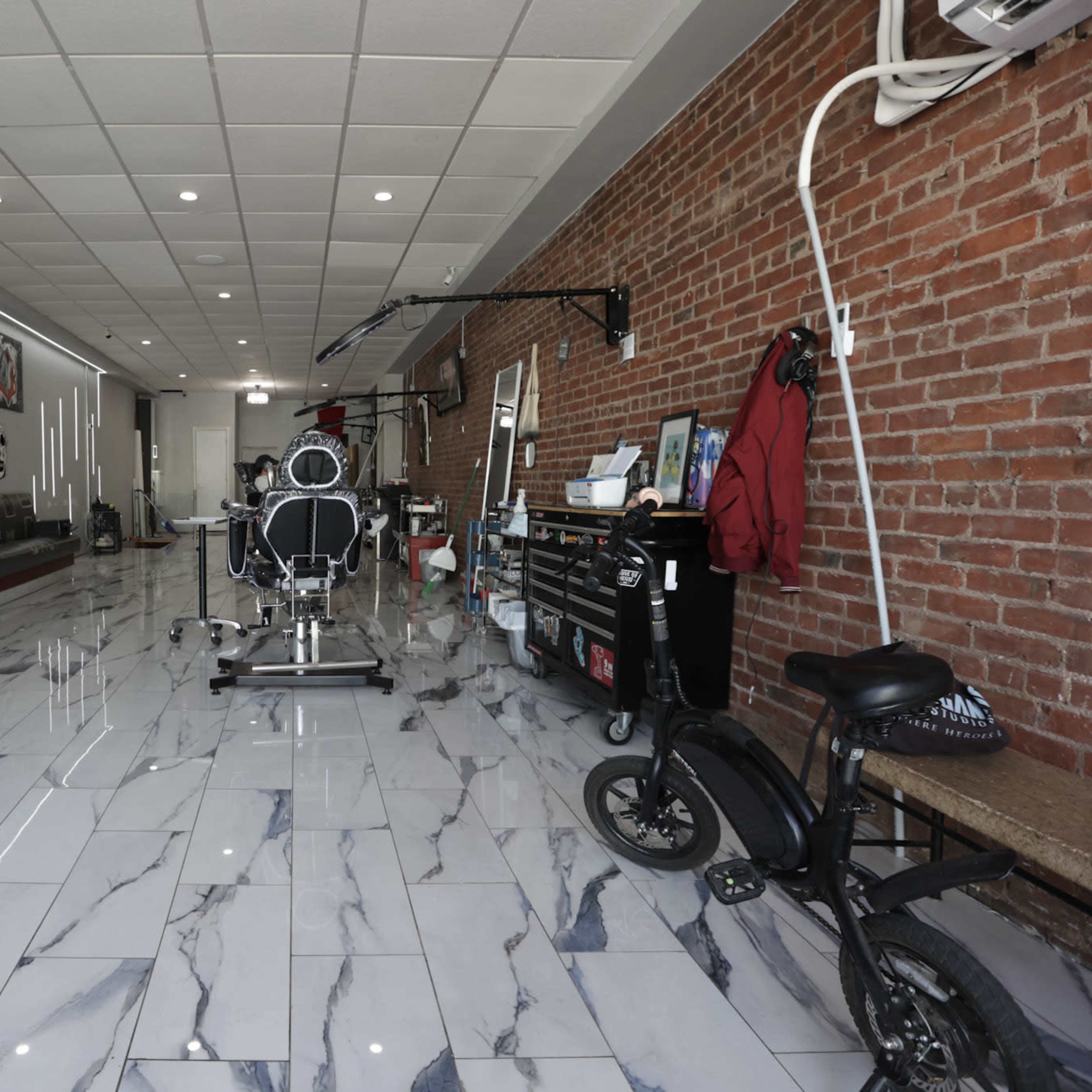 A spacious barbershop with a brick wall, tiled flooring, and various art pieces displayed on the walls.