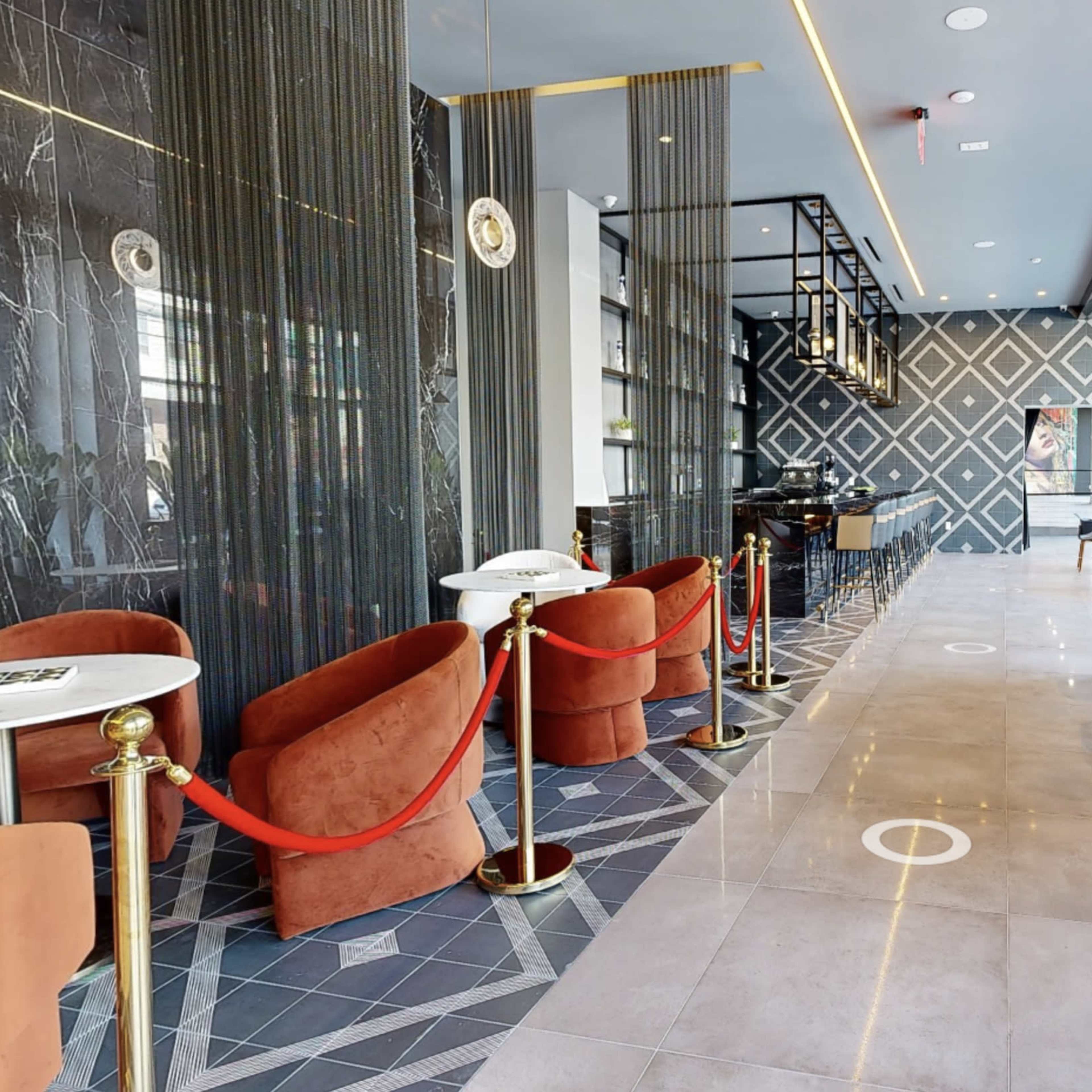 A modern café interior with a marble floor, sleek furniture, and a row of seats along large windows.