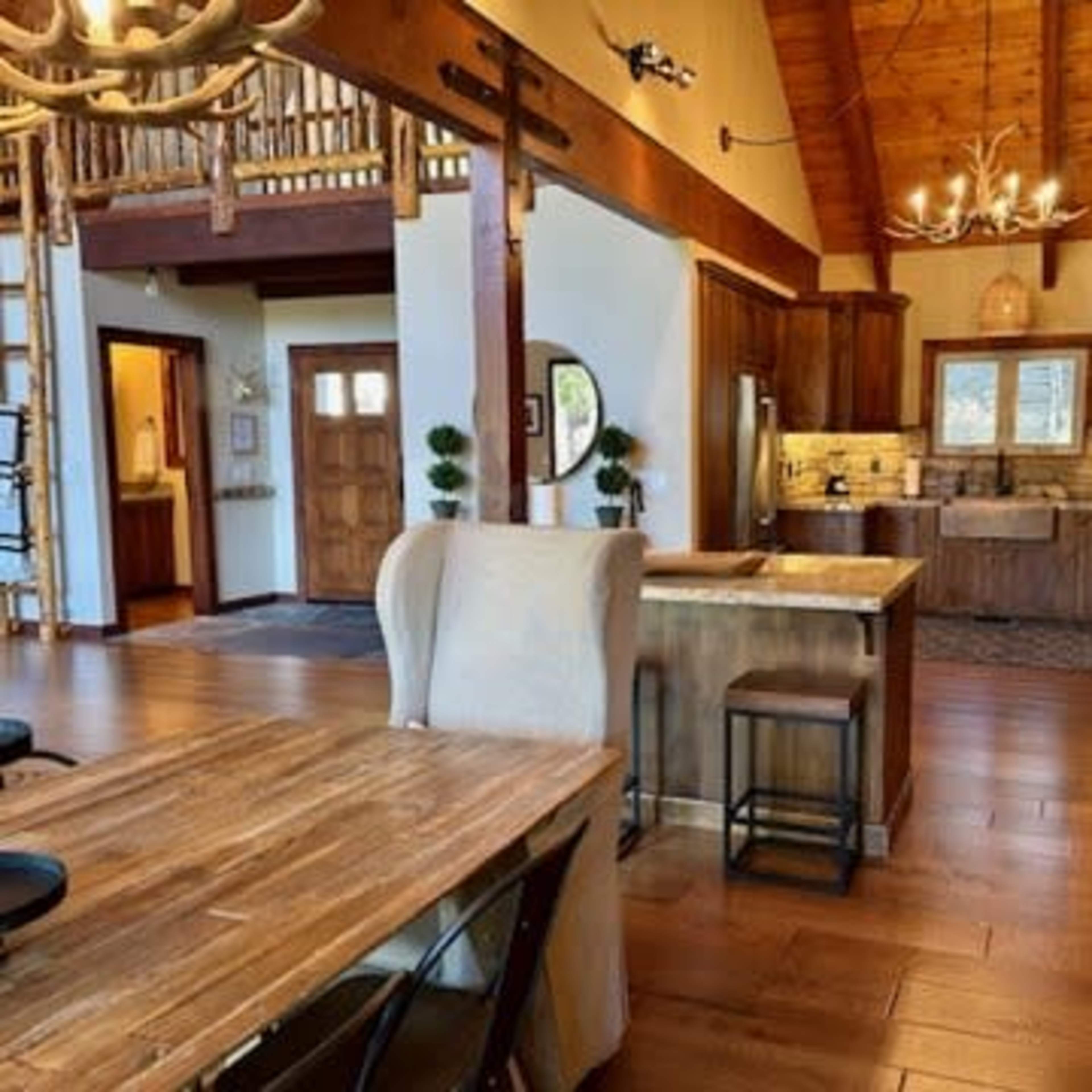 An open-concept kitchen and dining area with wooden beams, modern appliances, and a large central island.