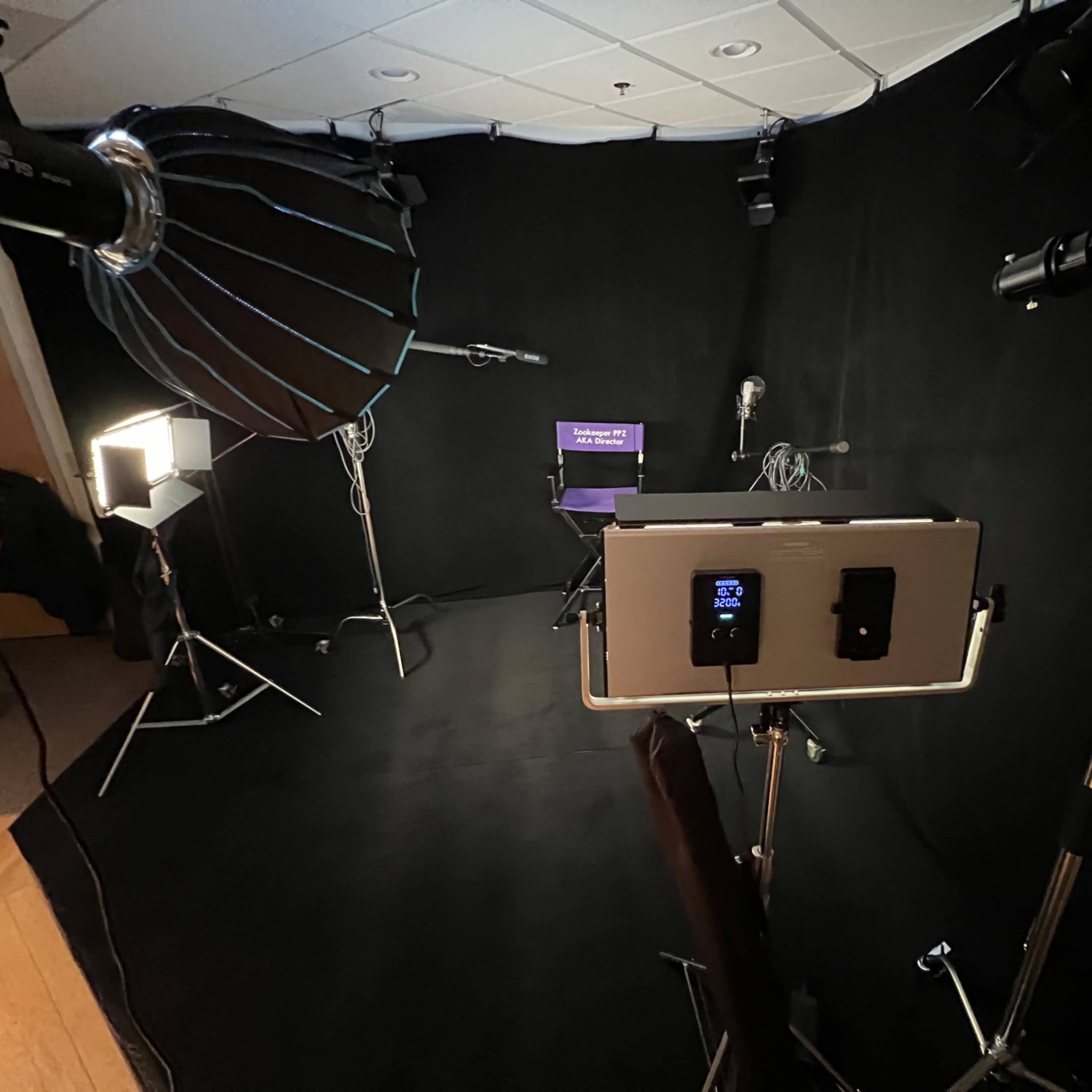 A dimly lit studio setup with multiple lighting fixtures and a chair positioned in front of a black backdrop.