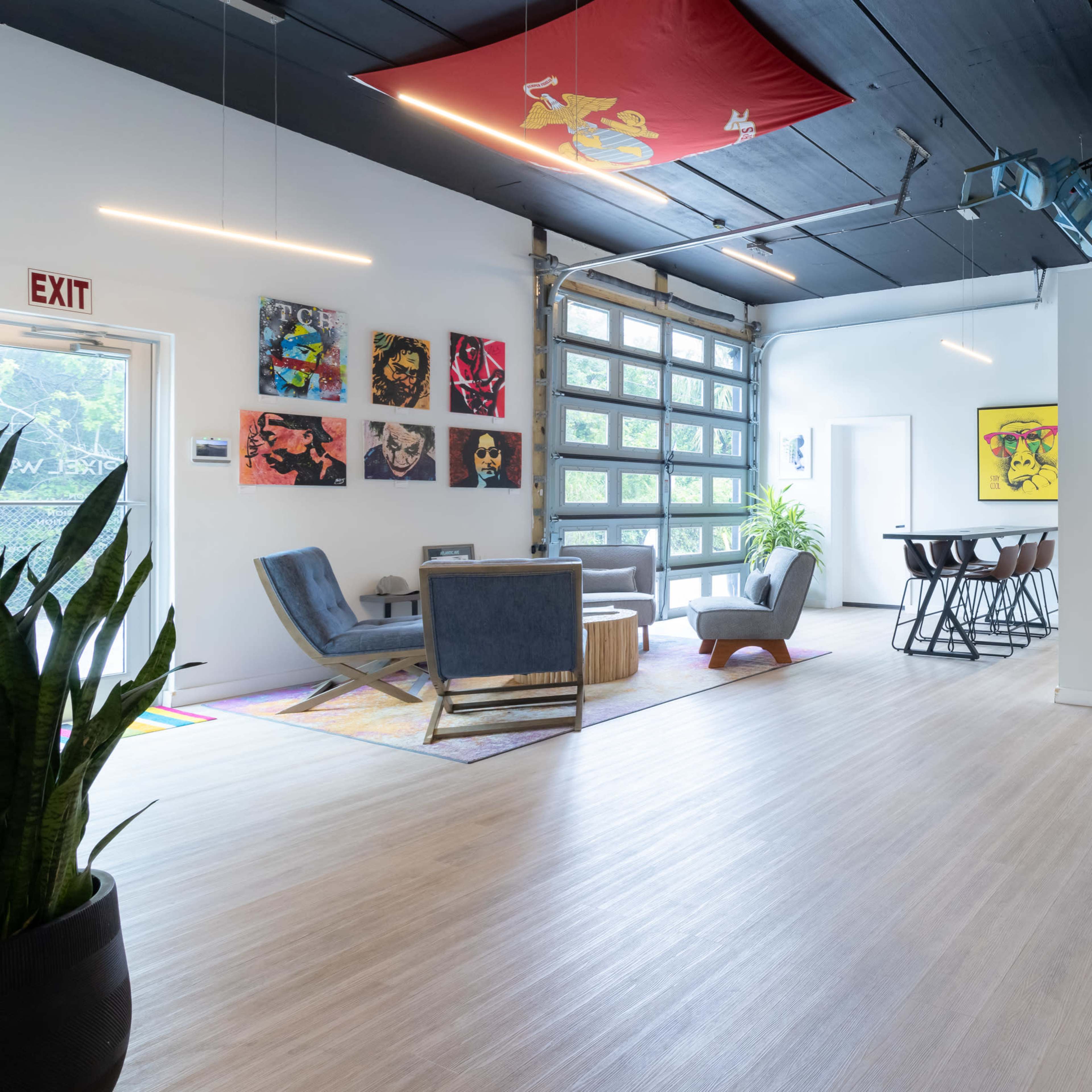 A spacious, modern interior with artwork on the walls, seating areas, and a large garage door.