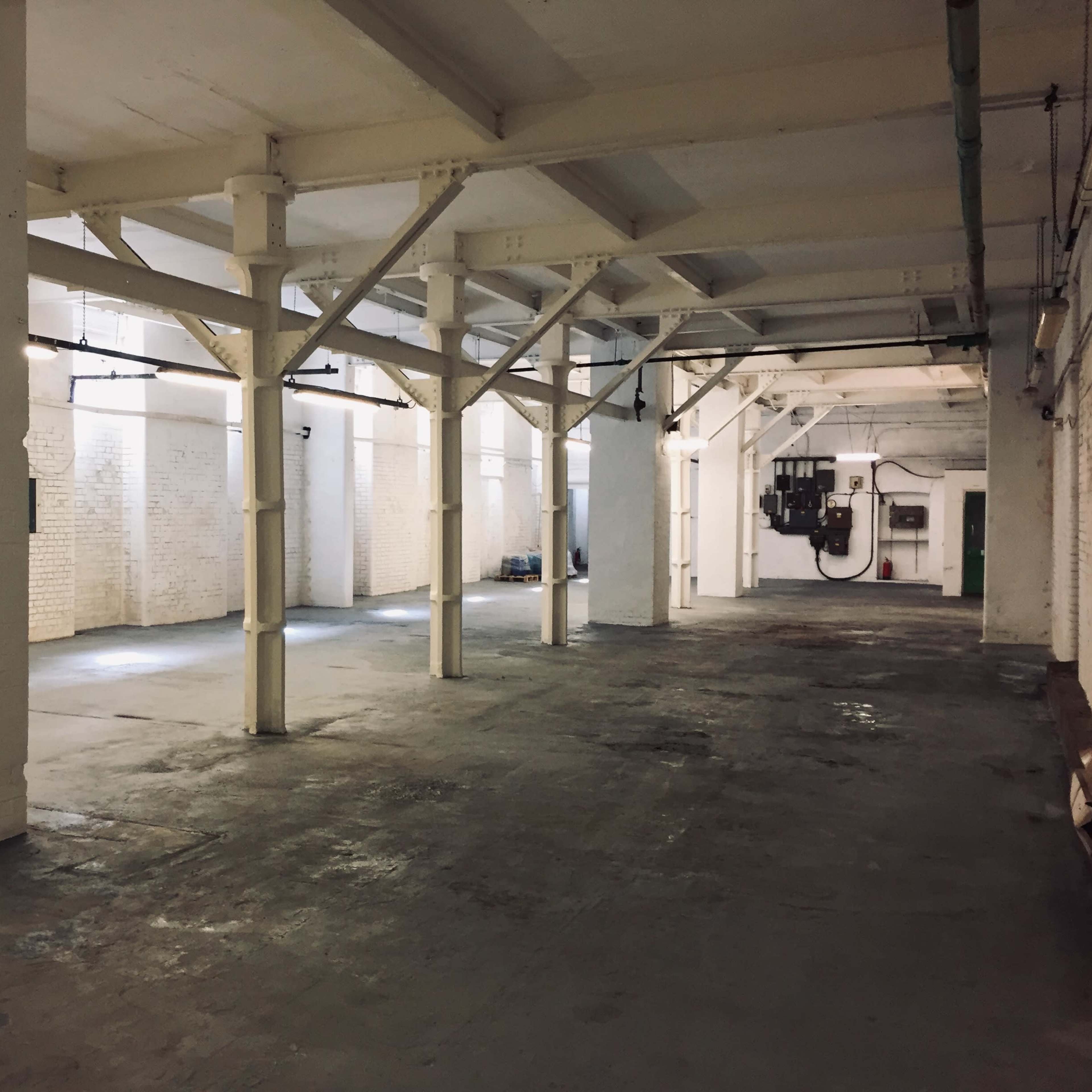 A spacious industrial interior with white walls, concrete flooring, and exposed structural beams.
