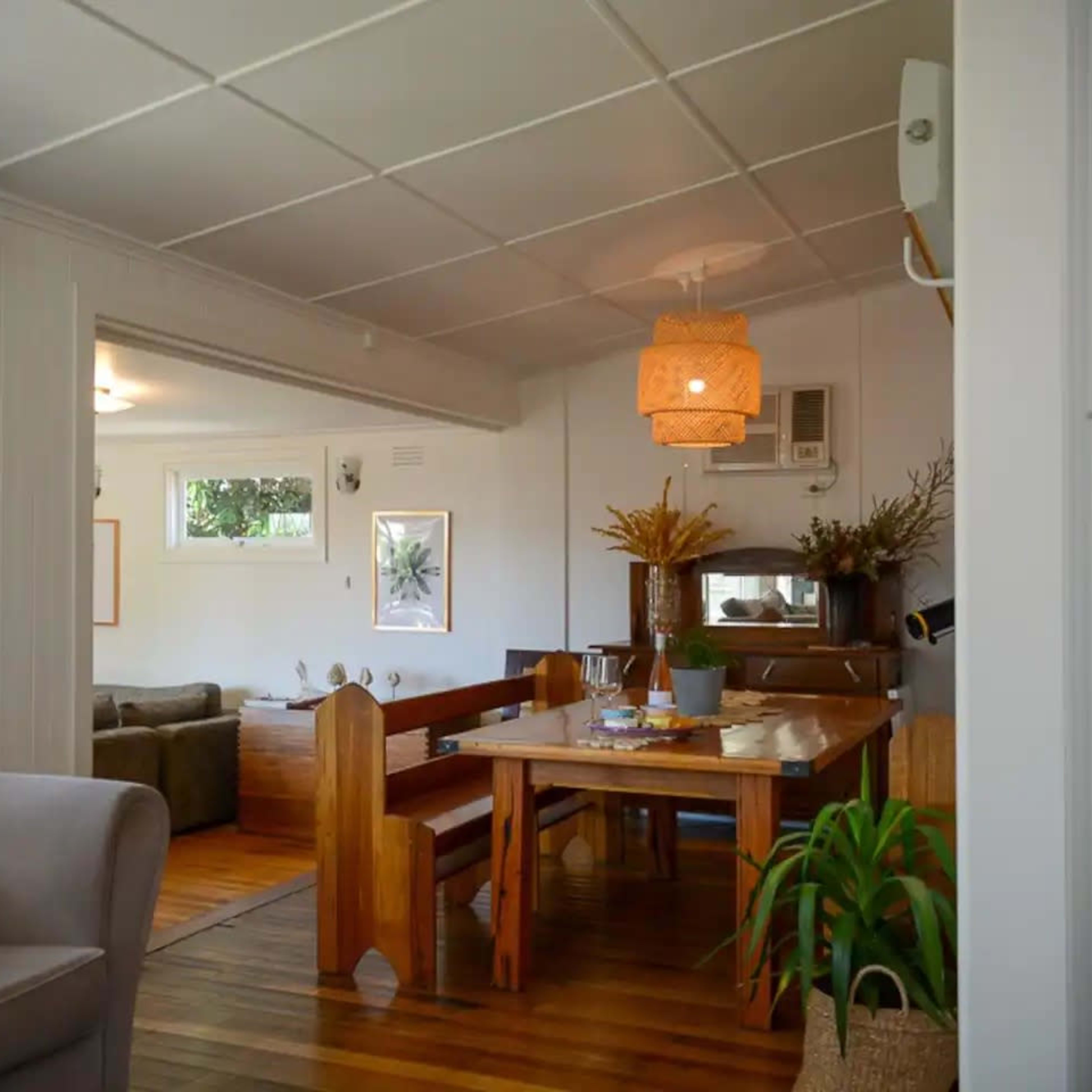 A spacious interior features a dining area with a wooden table, surrounded by chairs, and leads to a cozy living room area.