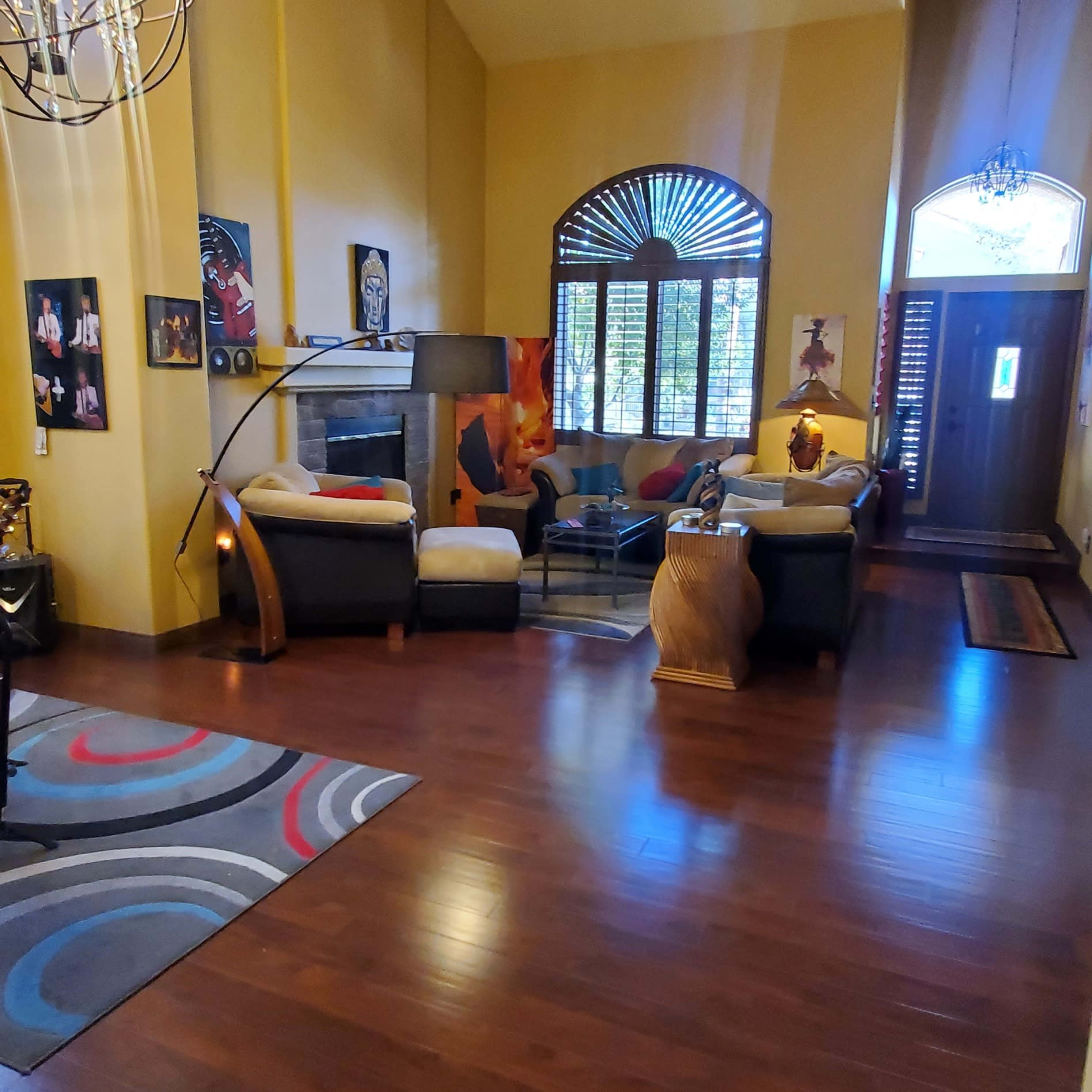 A spacious living room with high ceilings, large windows, and a mix of seating options arranged around a central coffee table.